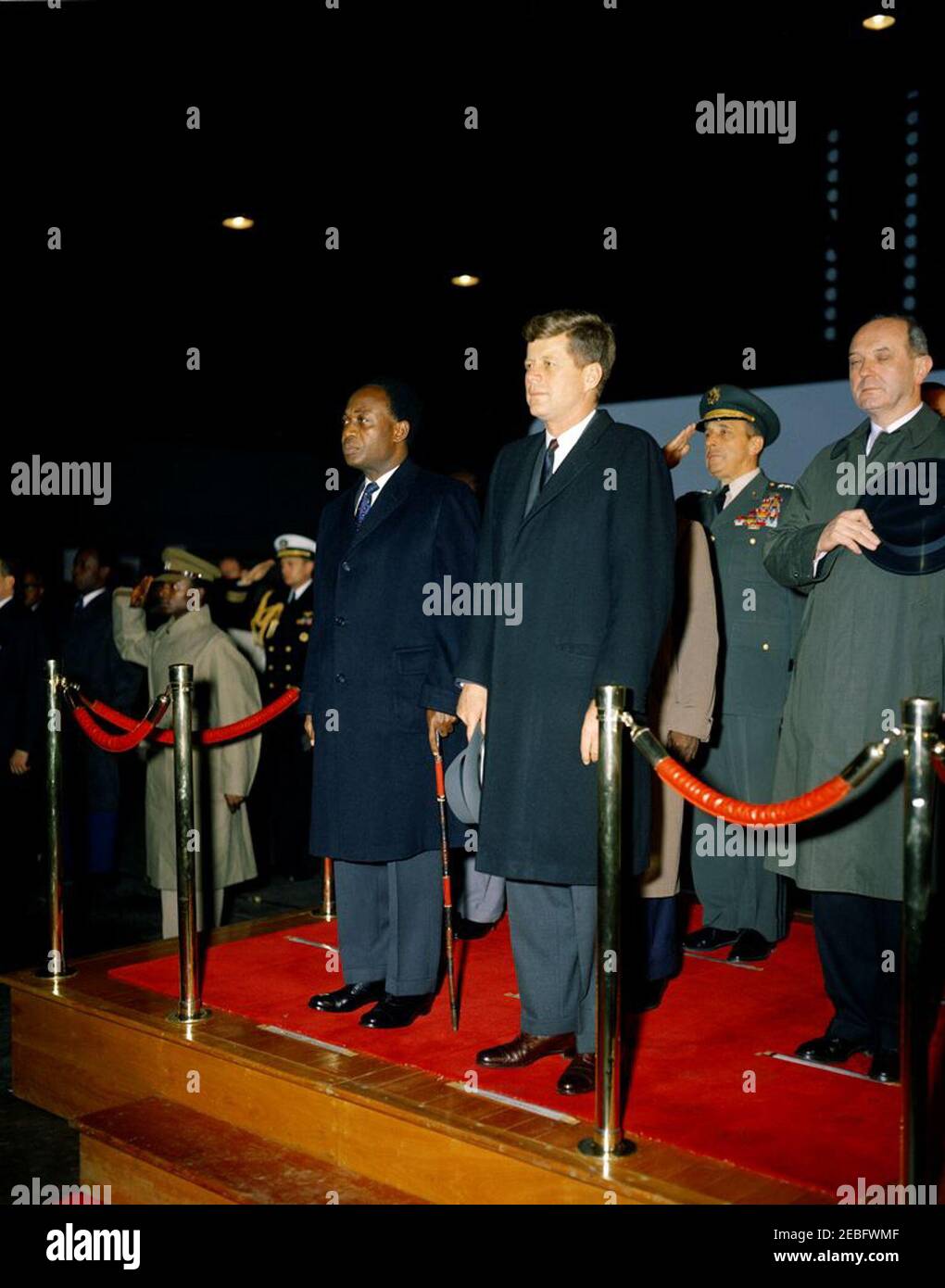 Cerimonia di arrivo per Kwame Nkrumah, presidente del Ghana, 15:43. Il presidente John F. Kennedy partecipa alle cerimonie di arrivo in onore del presidente della Repubblica del Ghana, Osagyefo Dr. Kwame Nkrumah. Sulla piattaforma (L-R): Presidente Nkrumah; Presidente Kennedy; Presidente dei Capi di Stato congiunti, Generale Lyman Lemnitzer; Segretario di Stato, Dean Rusk. Anche nella foto: Naval Aide al presidente, Comandante Tazewell Shepard. Hangar n. 10, Terminal del Servizio militare di trasporto aereo (MATS), Aeroporto Nazionale di Washington, Washington, D.C. Foto Stock