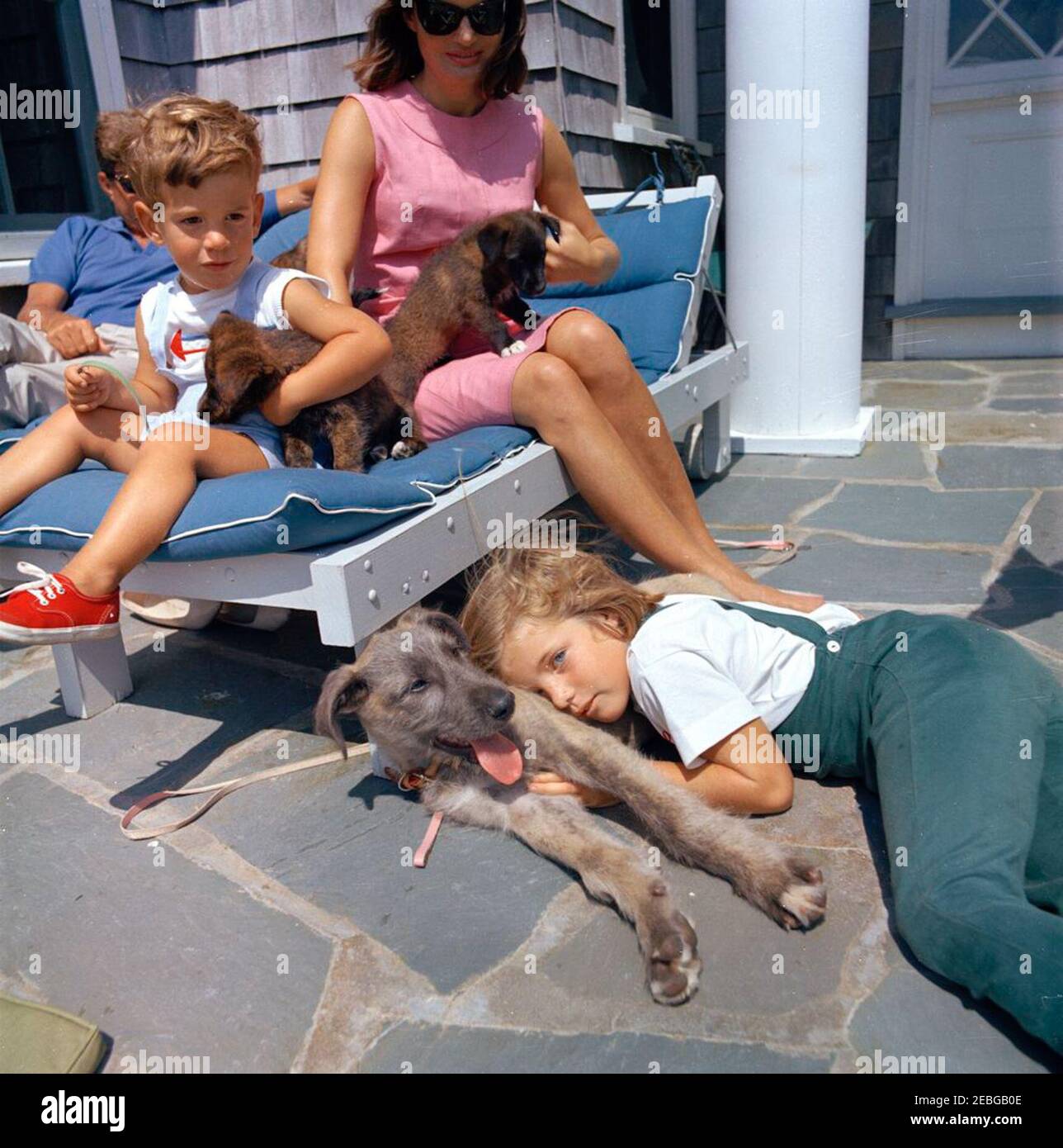 Viaggio a Hyannis Port u2013 Squaw Island, 1963-08-14. Il presidente John F. Kennedy (parzialmente nascosto), First Lady Jacqueline Kennedy, e i loro figli, Caroline Kennedy e John F. Kennedy, Jr., siedono con i loro cani, Wolf, White Tips, e Blackie, a casa Brambletyde su Squaw Island, Hyannis Port, Massachusetts. Foto Stock