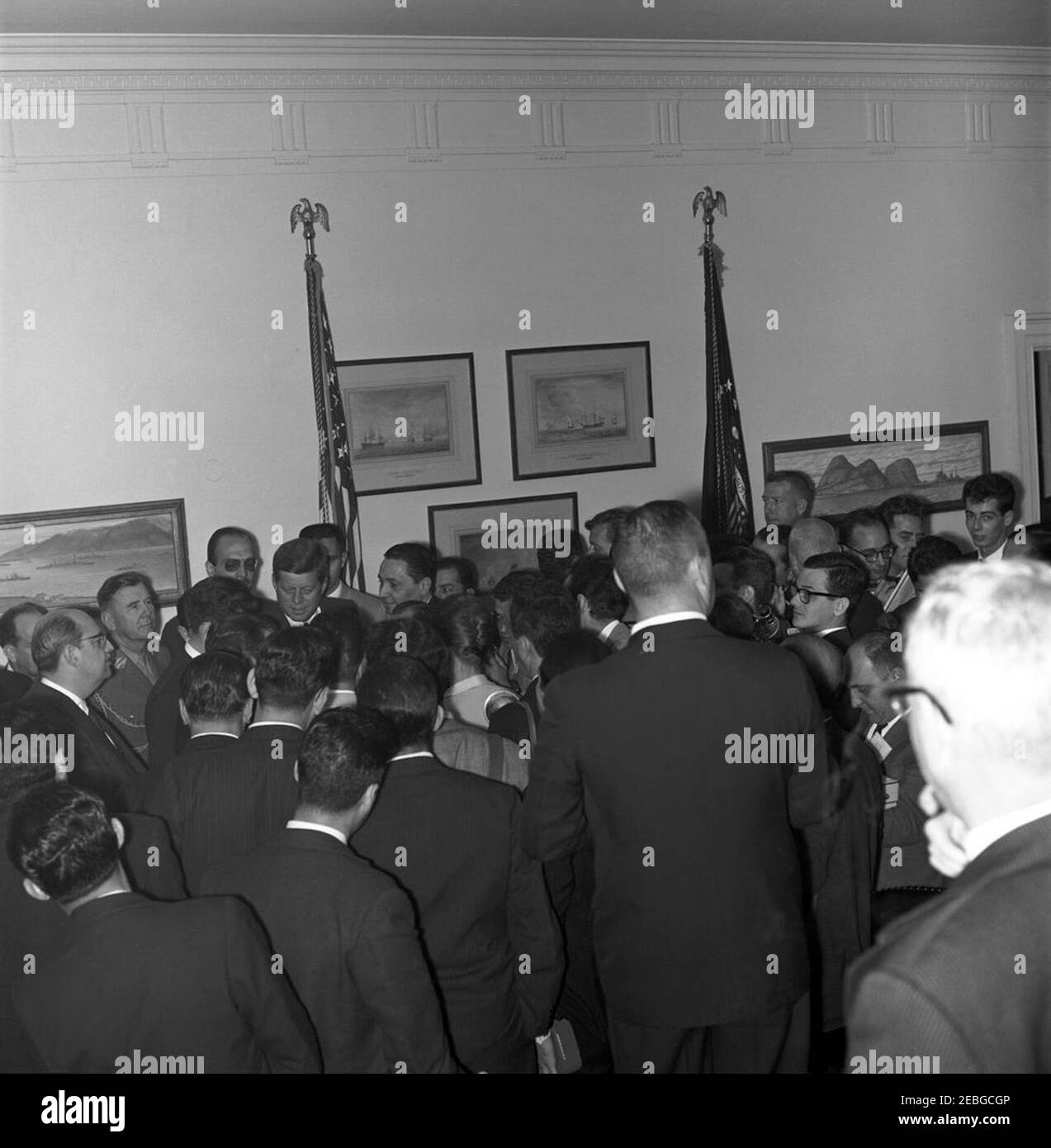 Incontro con Jou00e3o Goulart, presidente del Brasile, 16:40. I giornalisti sudamericani circondano il presidente John F. Kennedy (a sinistra) e il presidente del Brasile Jou00e3o Goulart (per lo più nascosto, a sinistra del presidente Kennedy) nella Sala dei pesci della Casa Bianca durante una visita di addio. Il ministro brasiliano degli Affari Esteri Francisco Clementino San Tiago Dantas (in profilo, indossando gli occhiali) e il generale Amaury Kruel, capo della Casa militare del presidente Goulart, si trovano dietro il presidente Kennedy all'estrema sinistra; l'agente del Servizio Segreto della Casa Bianca Arthur u201cArtu201d Godfrey (sul retro, a destra della bandiera) si erge a. Foto Stock