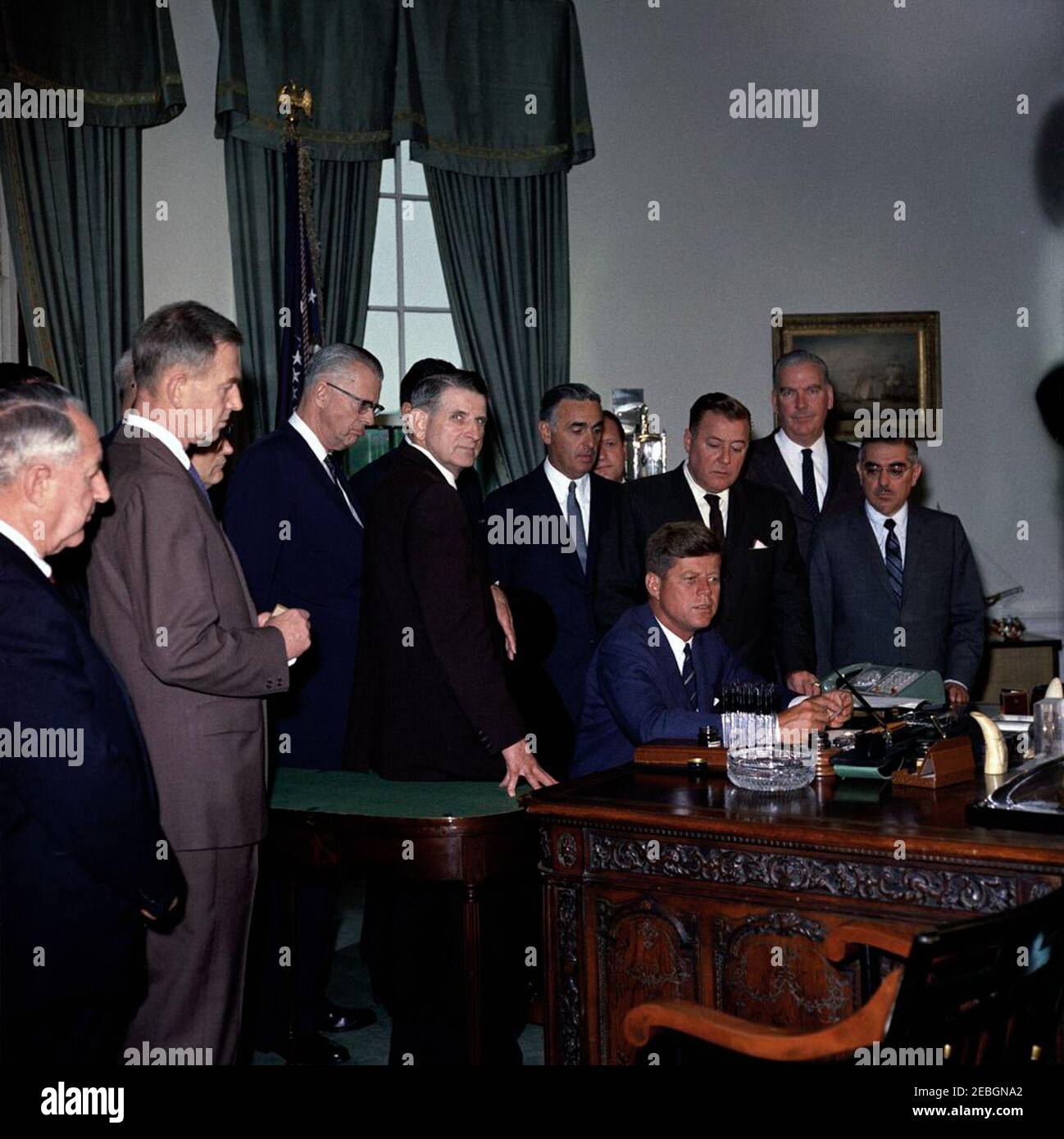 205 Legge pubblica 87-447, Legge sulla Televisione educativa, 12:00 PM. Il presidente John F. Kennedy (seduto) rilascia osservazioni dopo aver firmato la legge sulla televisione educativa. Stand (L-R): Unidentified; Senator Clifford P. Case (New Jersey); Congressman John E. Moss of California (dietro il Senator Case); Senator Norris Cotton (New Hampshire); Congressman Oren Harris (Arkansas); Secretary of Health, Education, and Welfare, Abraham Ribicoff; Avvocate, Leonard H. Marks (dietro); Senuson G. Warren (Washington); Magnuson (in); Magnuson); Magnator G. Springer (Illinois); il senatore John O. Pastore (Rhode i Foto Stock