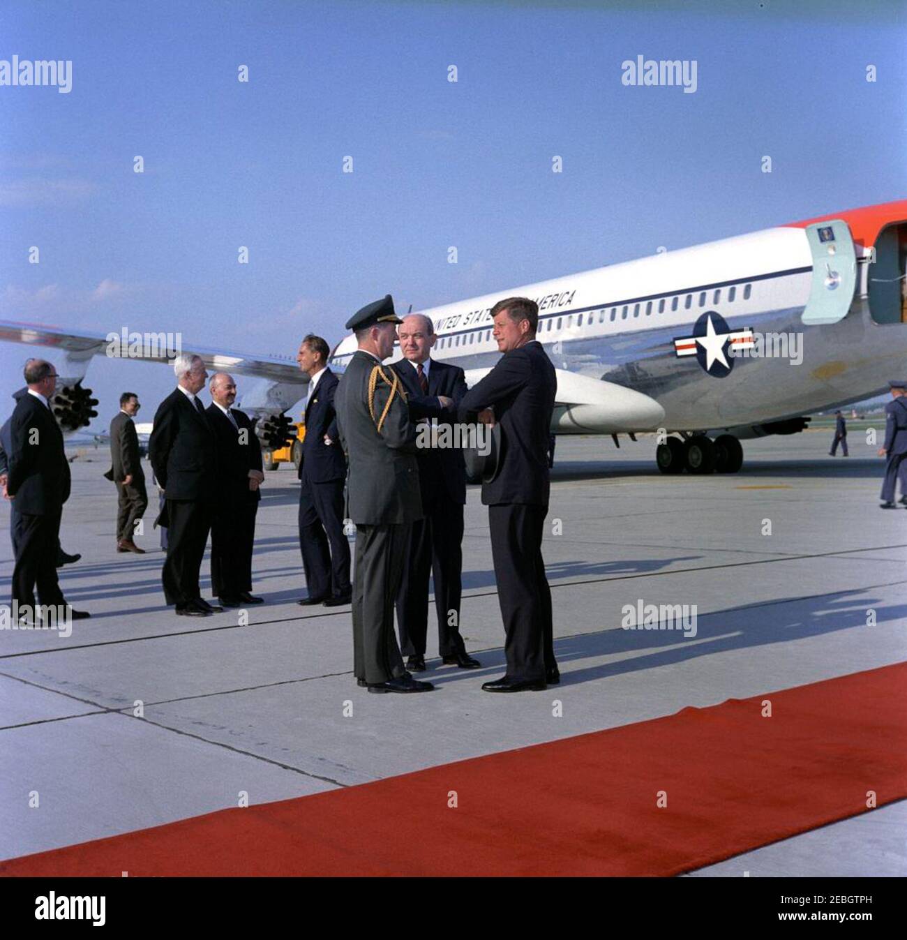 Il presidente Kennedy torna alla base dell'aeronautica di Andrews dalle vacanze di Pasqua, alle 16:33. Il presidente John F. Kennedy (cappello) parla con il Segretario di Stato, Dean Rusk (centro), e l'Aide militare al presidente, General Chester V. Clifton, al suo arrivo a bordo dell'Air Force One alla base dell'aeronautica di Andrews, Maryland, dopo la vacanza di Pasqua a Palm Beach, Florida. Anche nella foto (sullo sfondo a sinistra): Direttore dell'Ufficio del Commonwealth britannico e degli Affari del Nord Europa, William C. Burdett, Jr.; ambasciatore degli Stati Uniti in Gran Bretagna, David K. E. Bruce; vice segretario aggiunto di sta Foto Stock