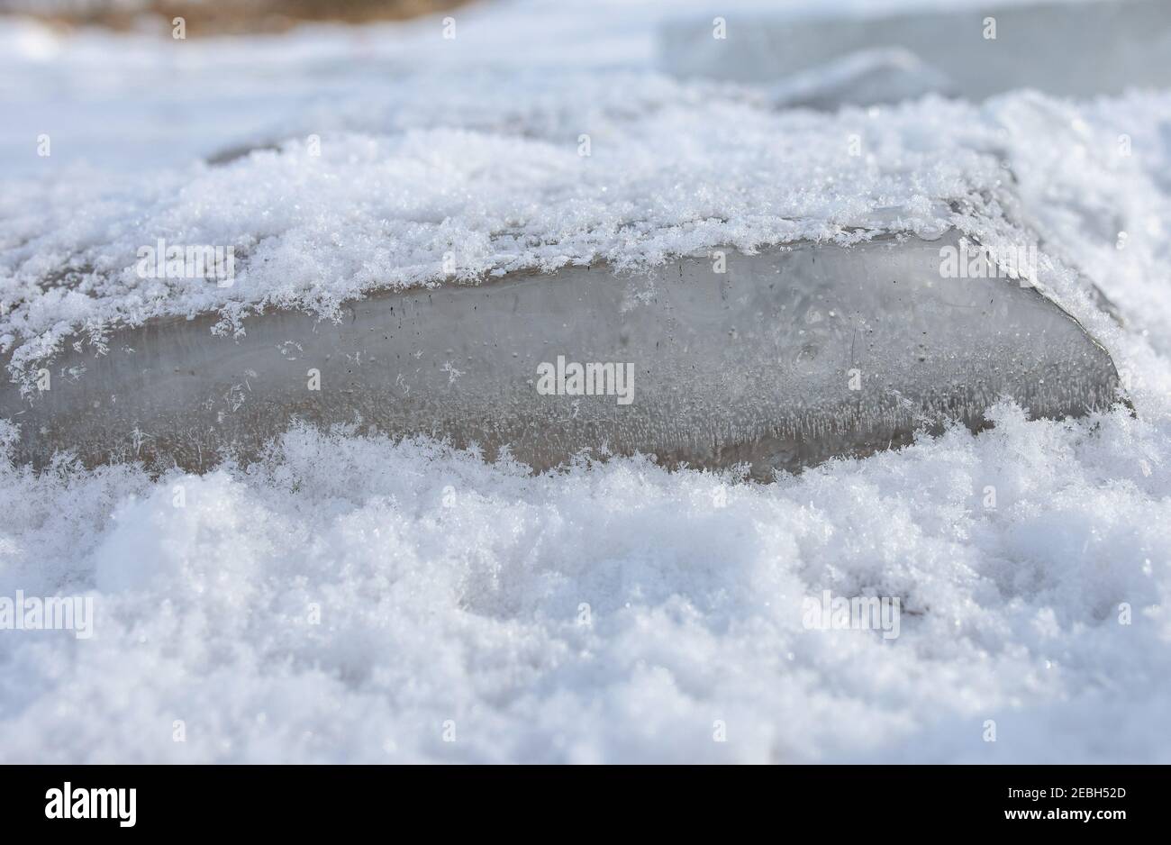 Pezzi di ghiaccio su un lago ghiacciato, spolverati di neve. Foto Stock