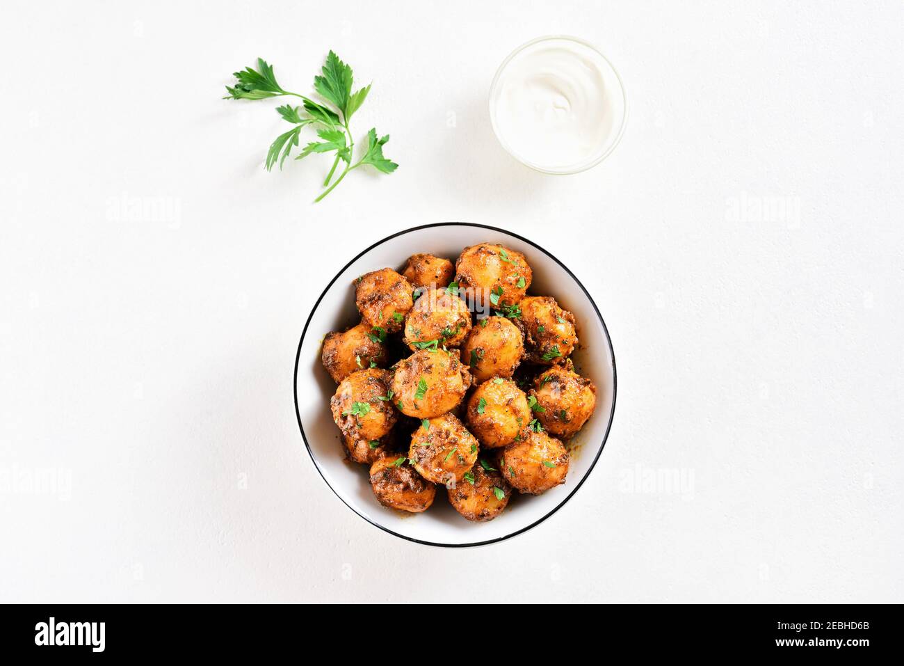 Patate Bombay. Pan patate fritte piccolo bambino con i semi di jeera e coriandolo in ciotola su sfondo chiaro con spazio libero di testo. Popolare piatto indiano. Foto Stock
