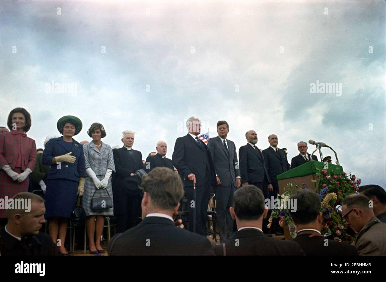 Viaggio in Europa: Irlanda, New Ross. Il presidente John F. Kennedy e altri illustri ospiti partecipano a una cerimonia di benvenuto per il presidente Kennedy a New Ross Quay, nella contea di Wexford, Irlanda. In piedi sulla piattaforma speakersu0027, in prima fila (L-R): Cognata del presidente Kennedyu0027s, Principessa Lee Radziwill della Polonia; non identificata; sorella del presidente 0027s, Jean Kennedy Smith; due inidentificate; Vice Presidente del Consiglio distrettuale urbano di New Ross, Gerald Donovan; Presidente; Presidente del Consiglio distrettuale urbano di New Ross, Andrew Minihan; Ministro degli Affari Esteri dell'Irlanda, p. Foto Stock