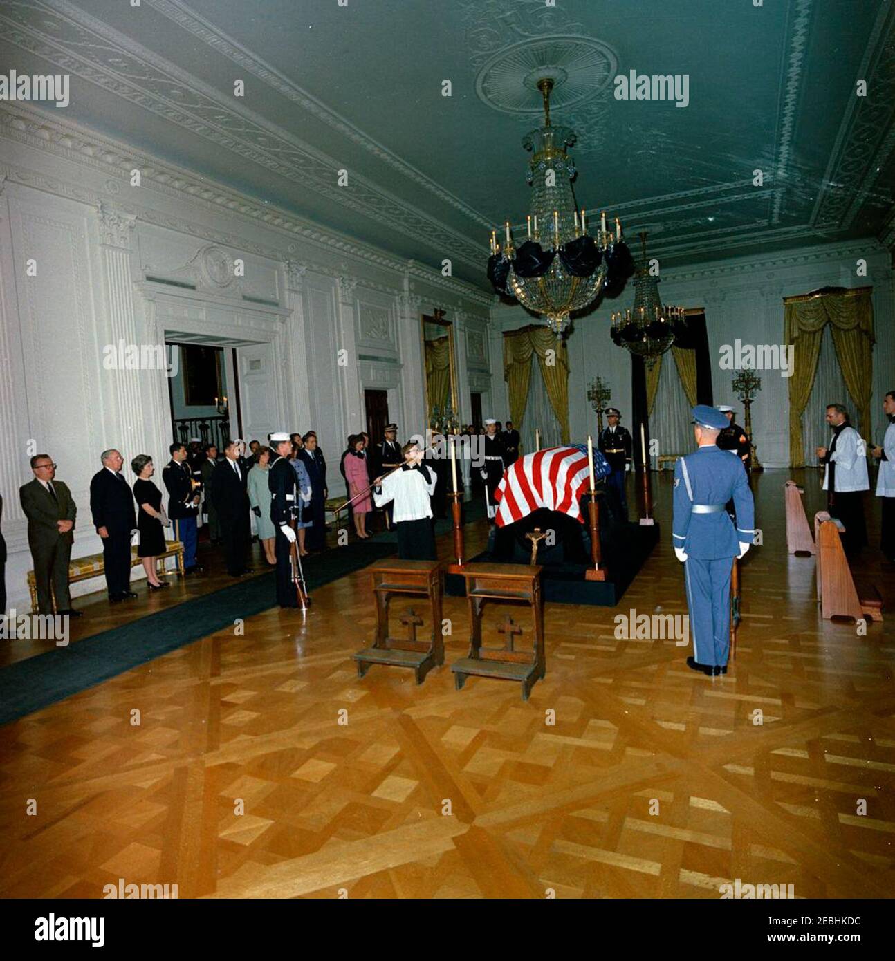 Funerali di Stato del Presidente Kennedy: Giacere in riposo nella stanza orientale della Casa Bianca. Il defunto presidente John F. Kennedy si trova in riposo nella stanza orientale; il casket con bandiera del presidente Kennedyu2019 si trova al centro, dopo l'arrivo del suo bodyu2019 alla Casa Bianca. I lutto osservano; i membri della guardia d'onore stand orologio. Le foto includono: First Lady Jacqueline Kennedy; Procuratore Generale Robert F. Kennedy; Jean Kennedy Smith; Ethel Skakel Kennedy; Direttore del corpo della Pace, R. Sargent Shriver; Janet Auchincloss; Hugh D. Auchincloss; Segretario della Difesa, Robert S. McNamara; Specia Foto Stock