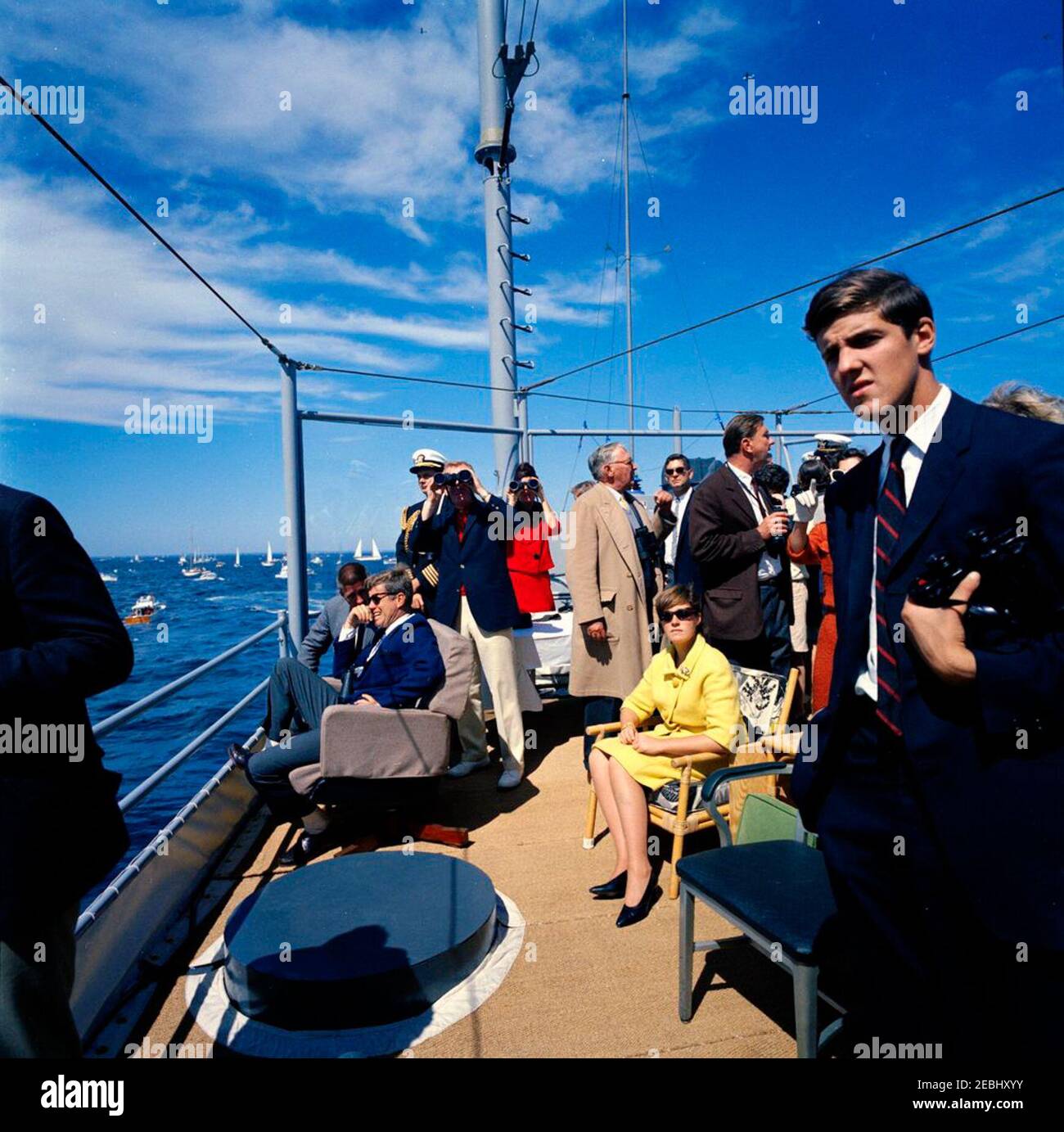 Il presidente Kennedy si accuda alla prima gara di Coppa Americau0027s. Il presidente John F. Kennedy (seduto a sinistra) guarda la prima gara della Coppa Americau0027s 1962 a bordo della USS Joseph P. Kennedy, Jr. Anche nella foto: Il senatore Benjamin A. Smith II (Massachusetts); l'Aide navale al presidente, il capitano Tazewell Shepard; sotto il segretario della Marina, Paul u0022Redu0022 Fay; Julia Ann Shepard; Hugh D. Auchincloss; Janet Jennings Auchincloss; Franklin D. Roosevelt, Jr.; John Forbes Kerry. Newport, Rhode Island. Foto Stock