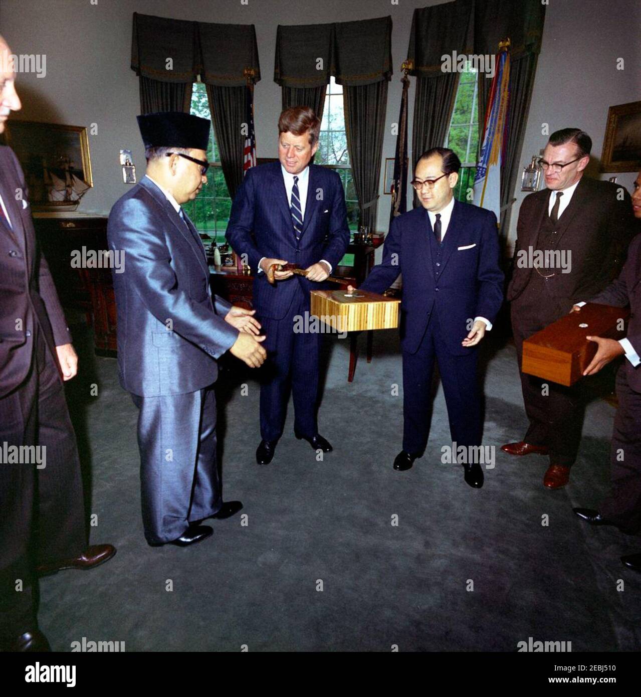 Incontro con Tun Abdul Razak, Vice primo Ministro della Malaya, 11:58. Il presidente John F. Kennedy scambia regali con il vice primo ministro e ministro della Difesa della Malaya, Tun Abdul Razak Hussein, durante un incontro nell'ufficio ovale. Da sinistra a destra: Ambasciatore degli Stati Uniti in Malaya, Charles F. Baldwin (sul bordo della cornice); Tun Razak; presidente Kennedy; ambasciatore della Malaya, Omar Ong Joke Lin; Segretario di Stato aggiunto degli Stati Uniti per gli affari dell'Estremo Oriente, Roger Hilsman; non identificato (sul bordo della cornice). White House, Washington, D.C. [vedi anche MO 74.334a-b, u0022Jeweled kris e sheathu0022] Foto Stock