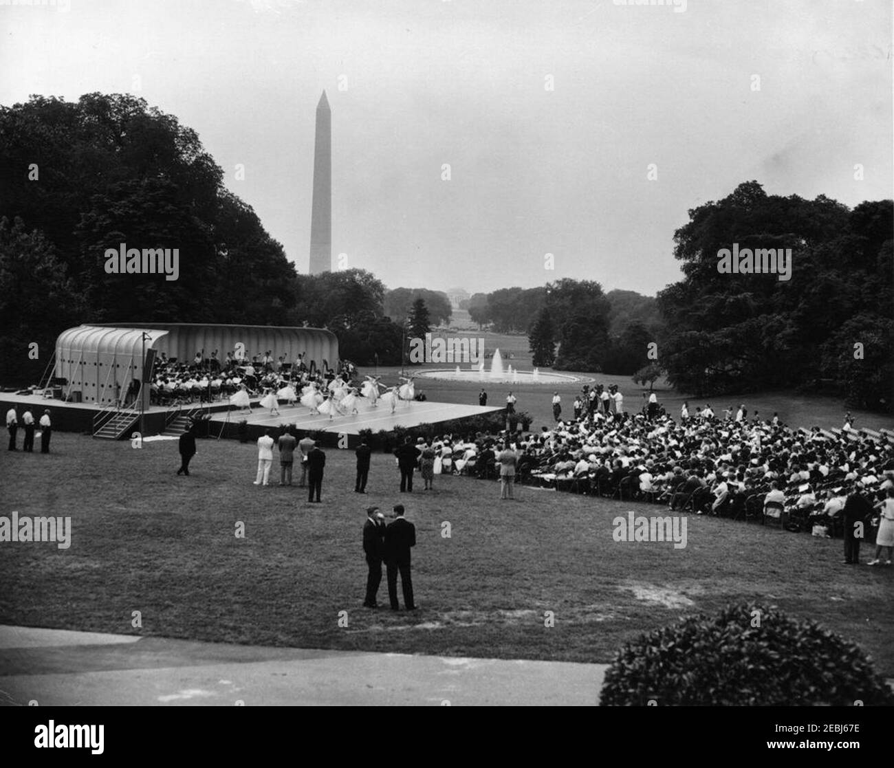 First Lady Jacqueline Kennedyu0027s (JBK) programma musicale per la gioventù, 10:35. Ampia vista del Prato Sud durante la quarta in prima Lady Jacqueline Kennedyu2019s serie di programmi musicali per la Gioventù. I ballerini di balletto e i membri della National High School Symphony Orchestra (entrambi del National Music Camp di Interlochen, Michigan) si esibiscono a sinistra in background; il presidente del National Music Camp, Dr. Joseph E. Maddy (in tribuna), dirige l'orchestra. Il Washington Monument e il Jefferson Memorial sono visibili in lontananza. White House, Washington, D.C. Foto Stock