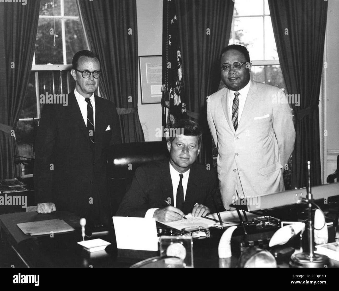 2399 Legge pubblica 87-633, designazione della casa di Frederick Douglass come parte del sistema del Parco nella capitale Nazionale, 9:45 AM. Il presidente John F. Kennedy firma una legge che designa la casa di Frederick Douglassu2019 come parte del sistema del parco nazionale nella capitale nazionale. Il senatore Philip A. Hart (Michigan) si trova a sinistra; il rappresentante Charles C. Diggs, Jr. (Michigan), si trova a destra. Ufficio ovale, Casa Bianca, Washington, D.C. Foto Stock