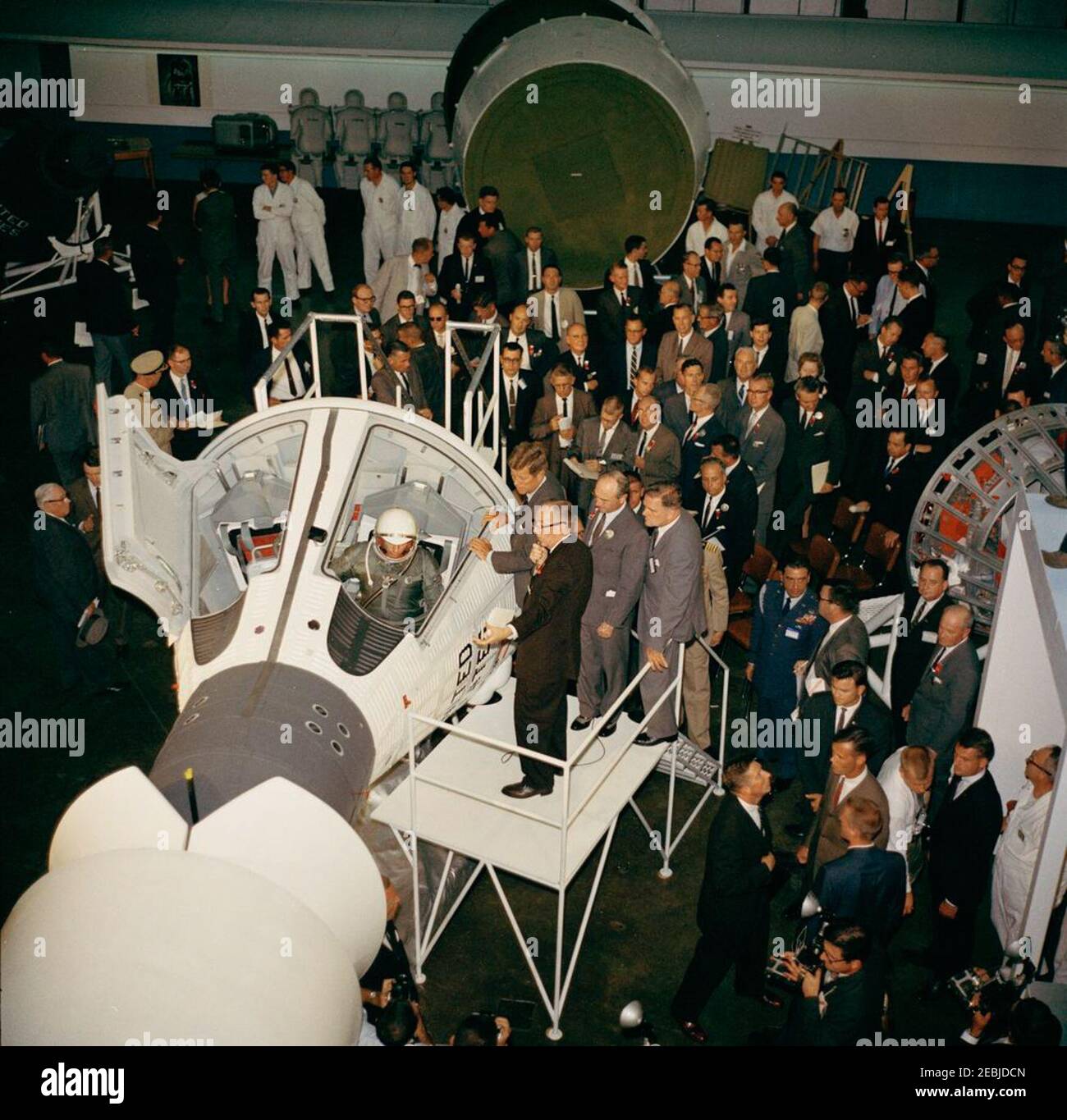 Visita delle installazioni della NASA: St. Louis, Missouri, McDonnell Aircraft, 15:27. Il presidente John F. Kennedy vede un mock-up della capsula spaziale Gemini, durante un tour della McDonnell Aircraft Corporation Plant a St. Louis, Missouri. Sulla piattaforma, in primo piano (L-R): Ingegnere McDonnell, Elbert Wiegand (seduto nell'abitacolo della navicella spaziale a due uomini); Vice Presidente della McDonnell Aircraft Corporation e Direttore Generale dei progetti Mercury e Gemini, Walter F. Burke (parlando al microfono); Presidente Kennedy; Presidente del Consiglio di Amministrazione e Amministratore Delegato del McDonnell Aircraft Foto Stock