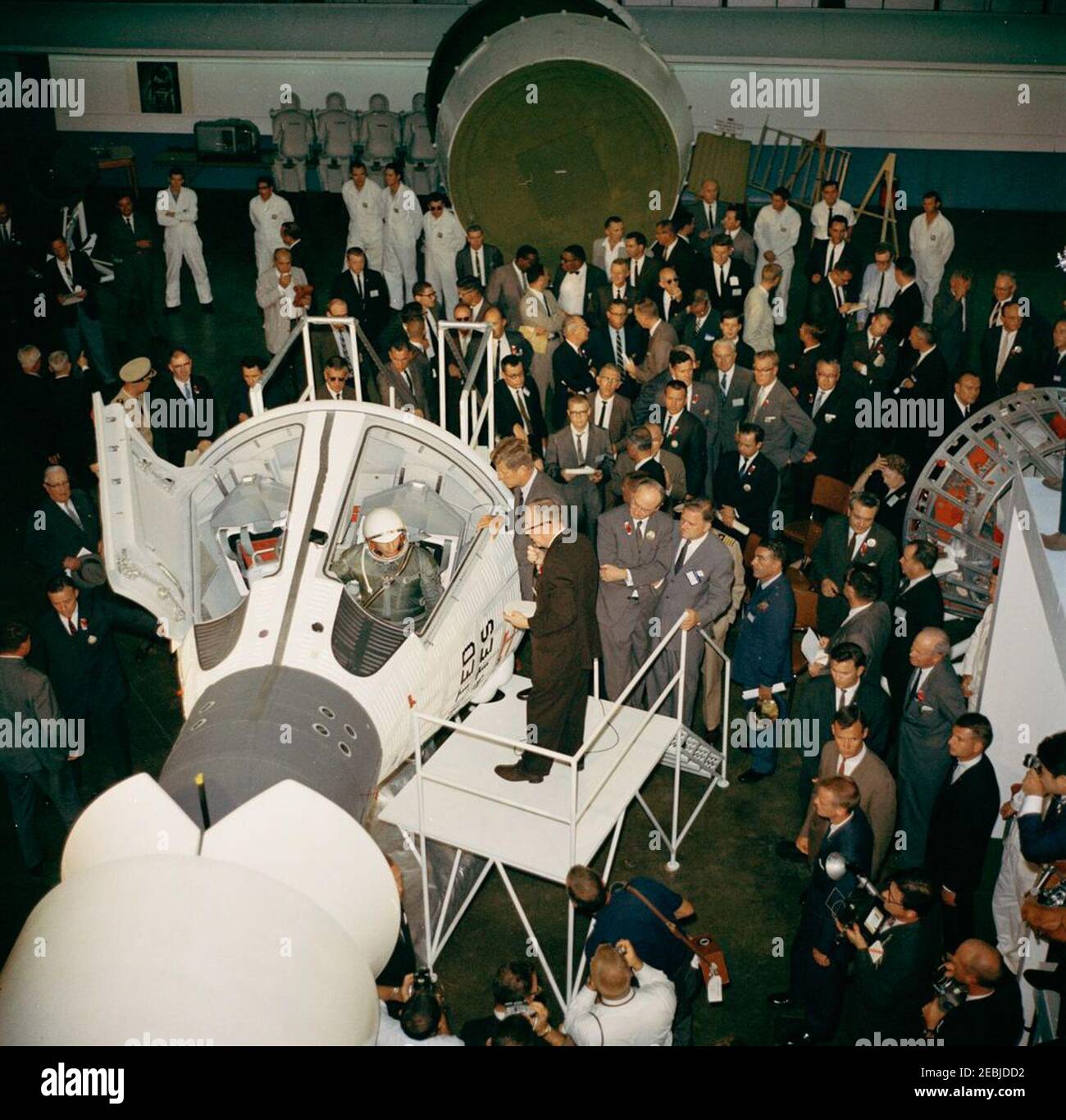 Visita delle installazioni della NASA: St. Louis, Missouri, McDonnell Aircraft, 15:27. Il presidente John F. Kennedy vede un mock-up della capsula spaziale Gemini, durante un tour della McDonnell Aircraft Corporation Plant a St. Louis, Missouri. Sulla piattaforma, in primo piano (L-R): Ingegnere McDonnell, Elbert Wiegand (seduto nell'abitacolo della navicella spaziale a due uomini); Vice Presidente della McDonnell Aircraft Corporation e Direttore Generale dei progetti Mercury e Gemini, Walter F. Burke (parlando al microfono); Presidente Kennedy; Presidente del Consiglio di Amministrazione e Amministratore Delegato del McDonnell Aircraft Foto Stock