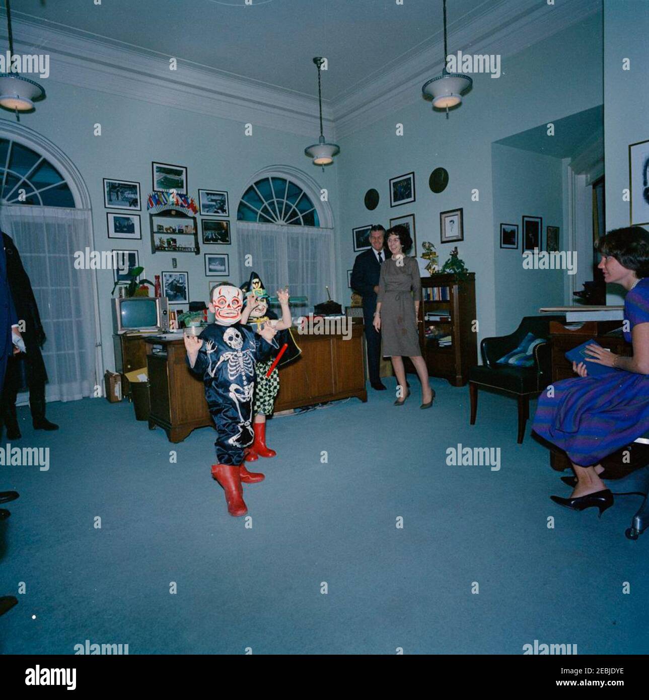 Bambini in costumi di Halloween. Caroline Kennedy (destra, parzialmente nascosta) e Steve Smith Jr. Posano nei loro costumi di Halloween. Guardando a: Presidente John F. Kennedyu2019s Segretario personale, Evelyn Lincoln; membro dello staff nell'ufficio della Sig.ra Lincolnu2019s, Priscilla Wear; Agente di Servizio segreto della Casa Bianca, Gerald A. u201cJerryu201d Behn. Ufficio del Segretario del Presidente 2019s, Casa Bianca, Washington, D.C. Foto Stock