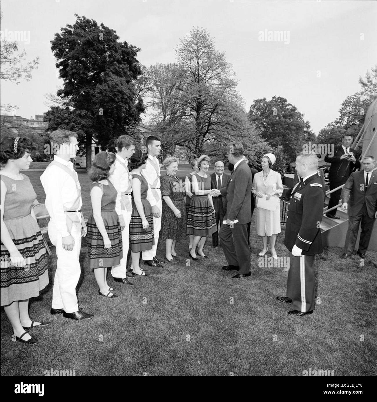 First Lady Jacqueline Kennedyu0027s (JBK) programma musicale per giovani, 14:10. Il presidente John F. Kennedy (centro, scuotendo le mani con una donna non identificata) saluta i membri del Berea (Kentucky) College Country Dancers sul prato sud della Casa Bianca, Washington, D.C. il gruppo di danza si è esibito come parte della sesta puntata di First Lady Jacqueline Kennedyu2019s Musical Programs for Youth by Youth. Il fotografo della Casa Bianca, Captain Cecil Stoughton (con la fotocamera), si trova sulle scale a destra; l'agente del Servizio segreto della Casa Bianca, Frank Yeager, si trova all'estrema destra. Un ai militare non identificato Foto Stock