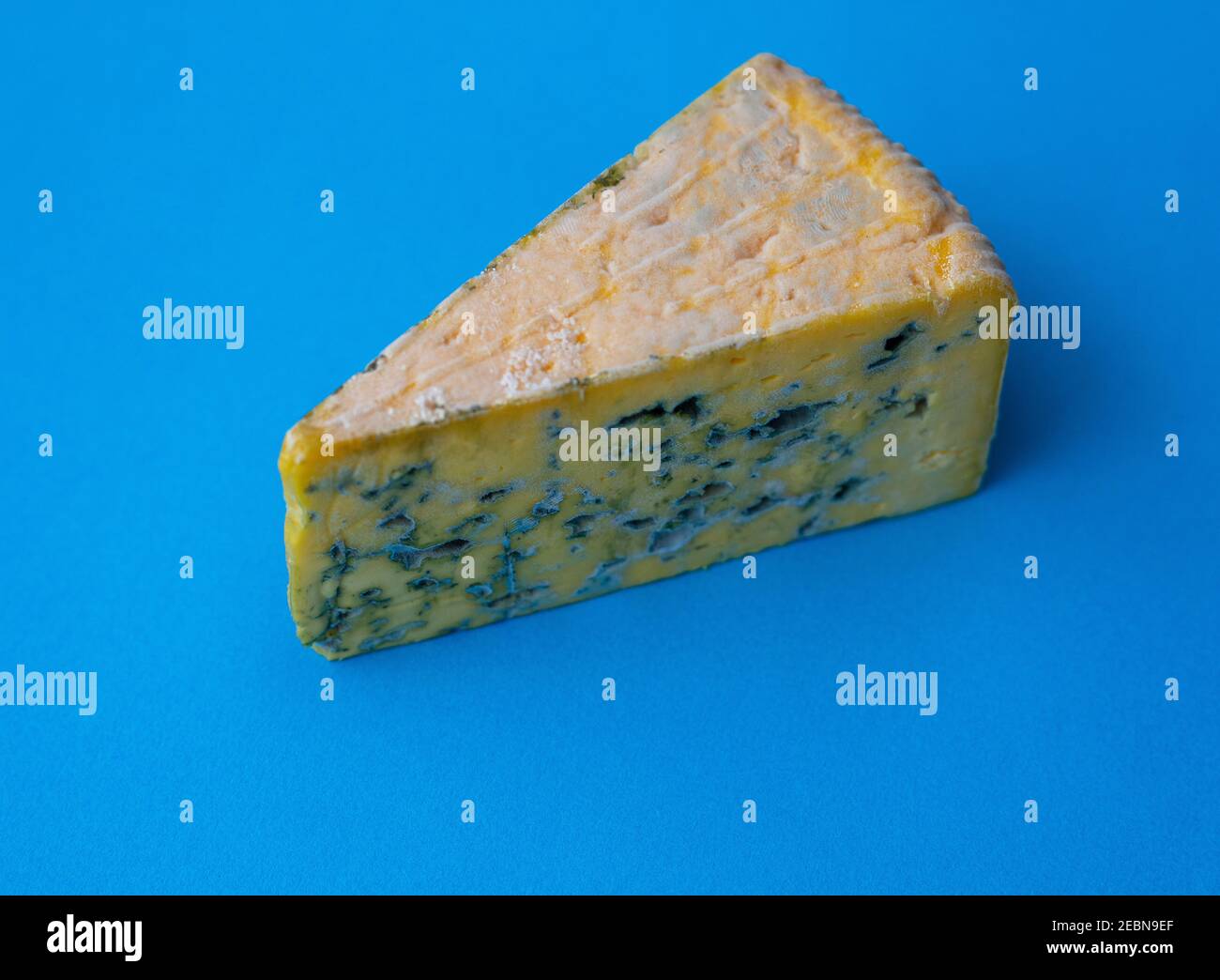 Pezzo di formaggio ammuffito su sfondo blu Foto Stock