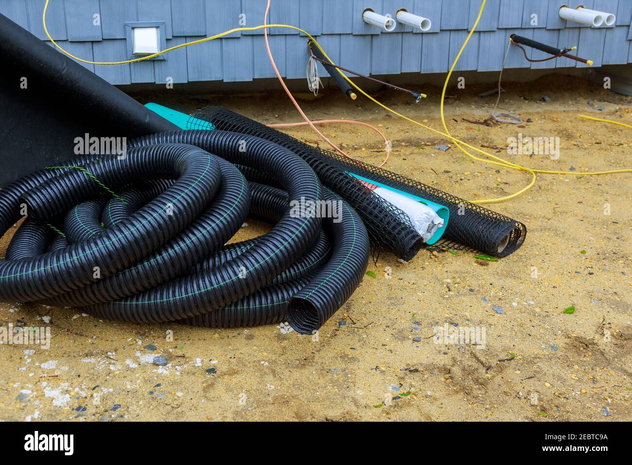 Il sistema di tubi di drenaggio di posa di utenze sotterranee da nero Tubi fognari in PVC di fognature di approvvigionamento Foto Stock