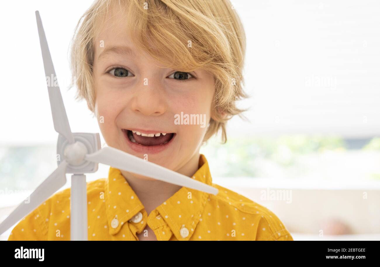 Ritratto di ragazzo sorridente (6-7) con modello a turbina eolica Foto Stock
