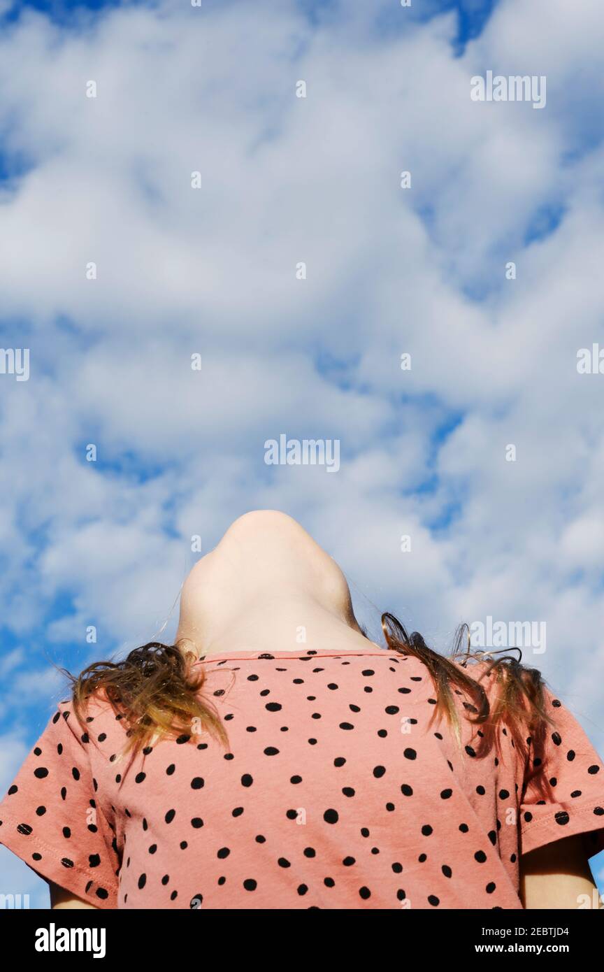 Vista ad angolo basso della ragazza (8-9) sotto il cielo nuvoloso Foto Stock