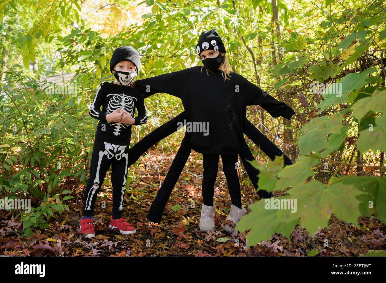 Ragazza (8-9) e ragazzo (6-7) che indossa i costumi di Halloween in foresta Foto Stock