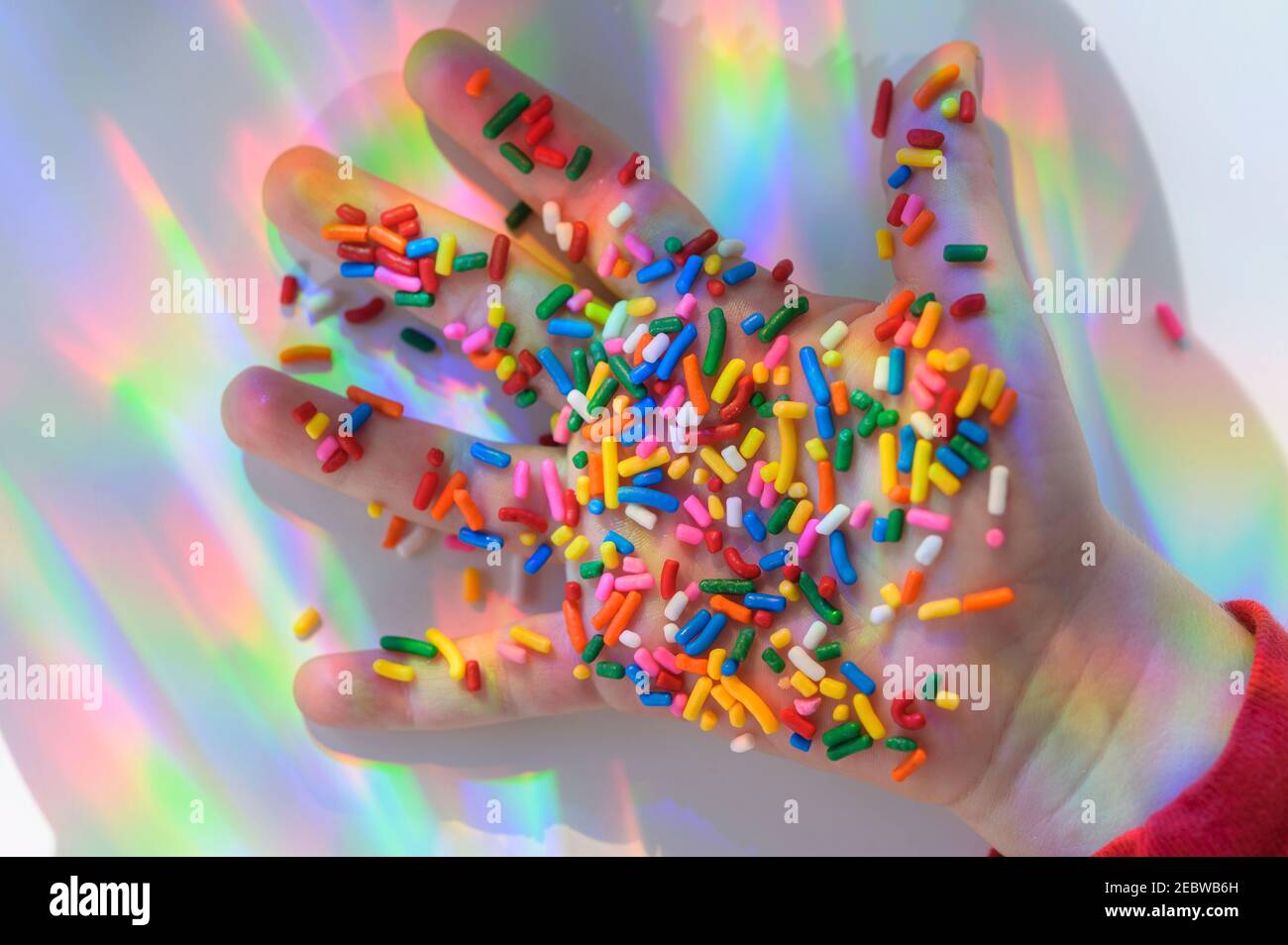 La mano tiene gli spruzzi con i riflessi colorati Foto Stock