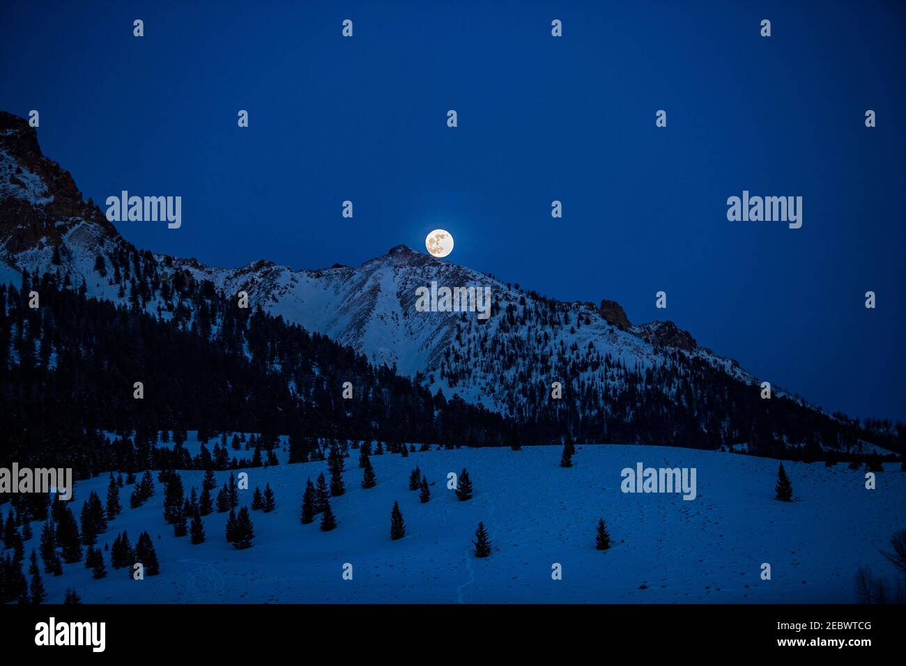 USA, Idaho, Sun Valley, Luna piena che si erge sulle Boulder Mountains nella notte invernale Foto Stock