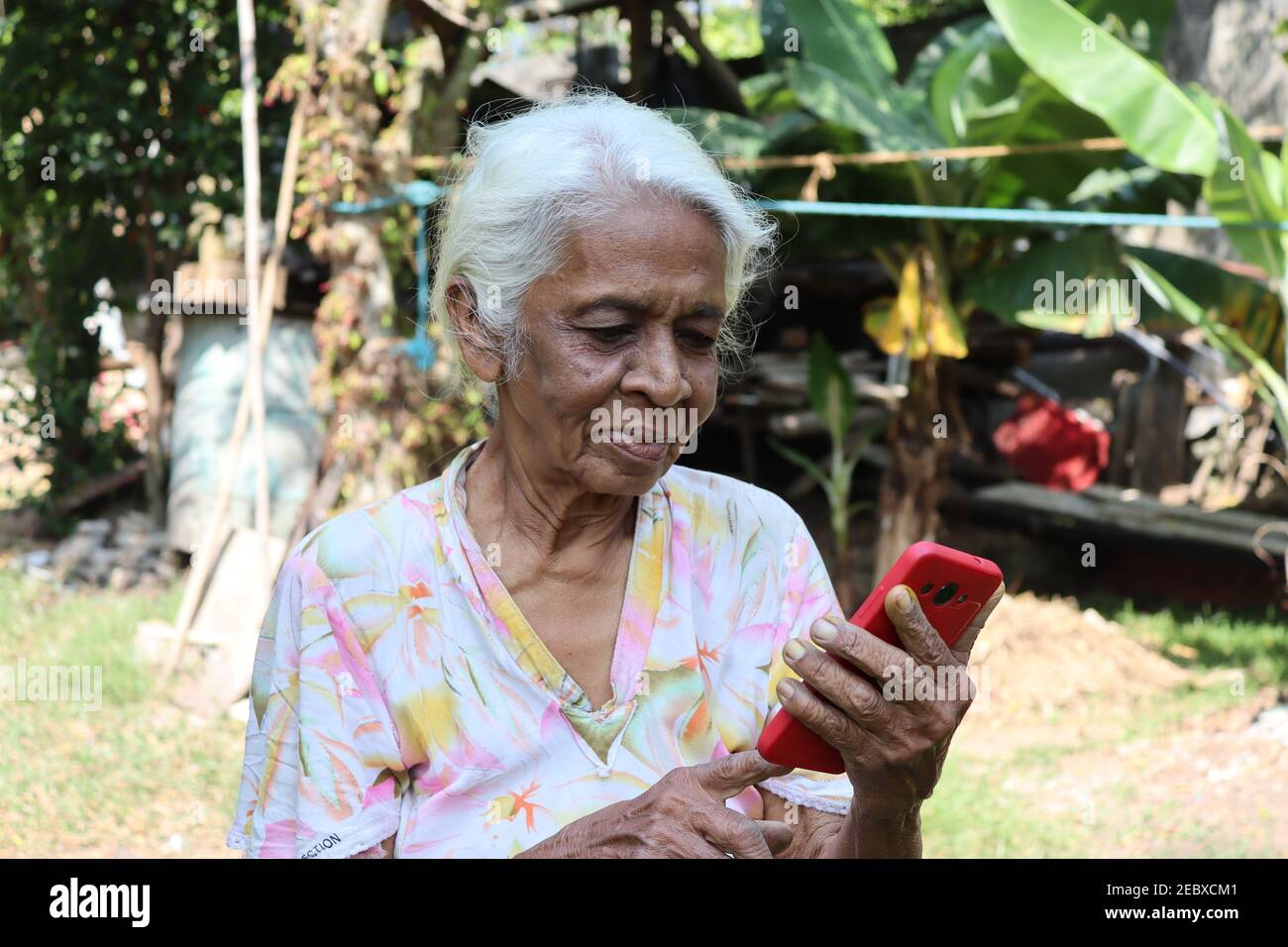 Sotto il tema "i negiors che usano la tecnologia attuale" la nonna usa la tecnologia moderna e la comunicazione a casa. Foto Stock