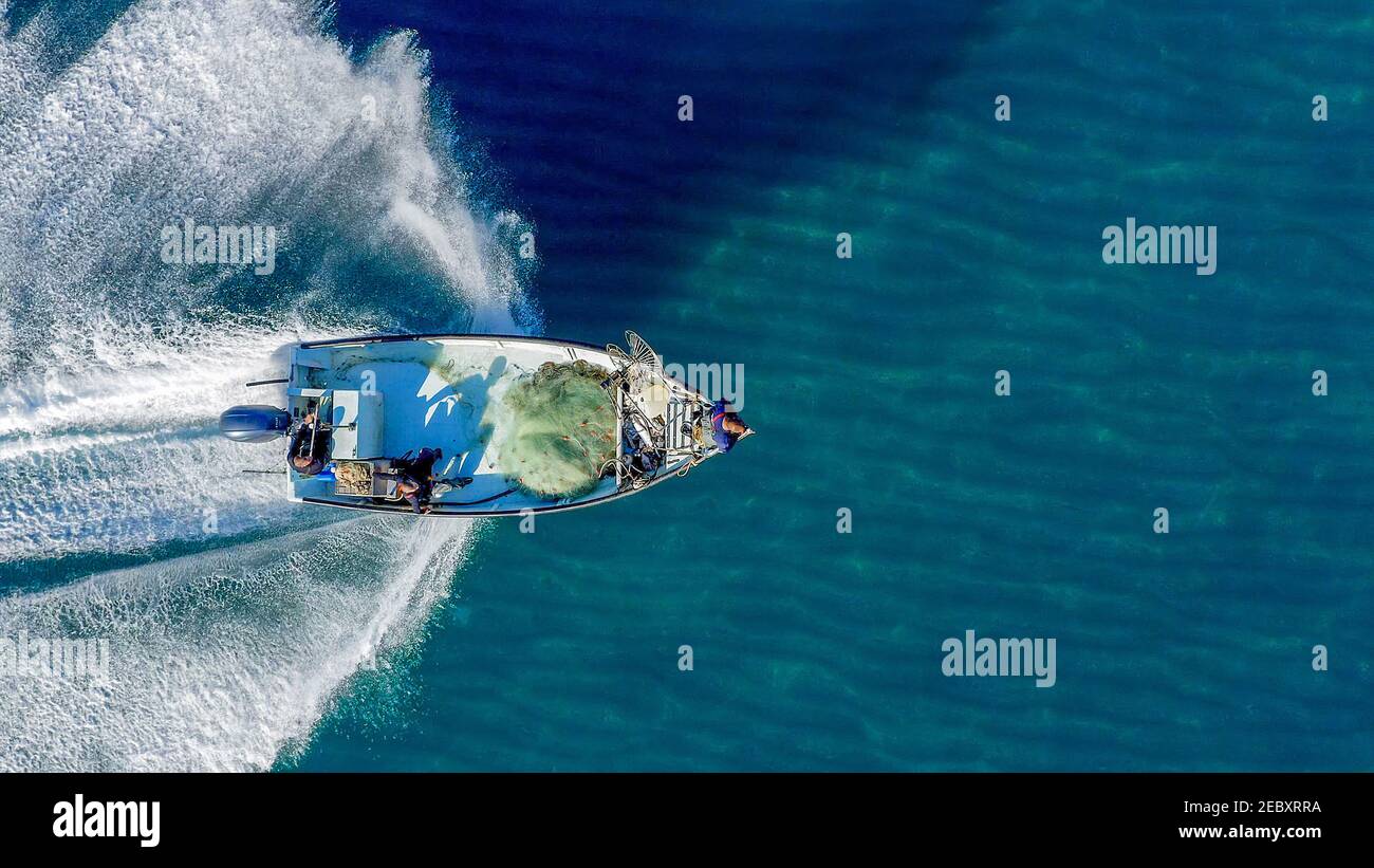 Piccola barca da pesca che si ruggisce attraverso il mare calmo e liscio, vista aerea. Foto Stock