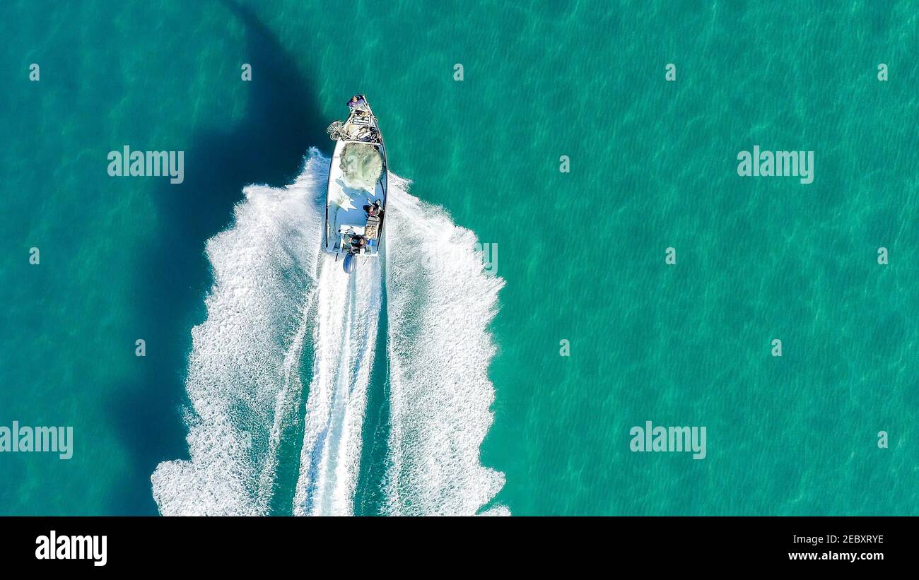 Piccola barca da pesca che si ruggisce attraverso il mare calmo e liscio, vista aerea. Foto Stock