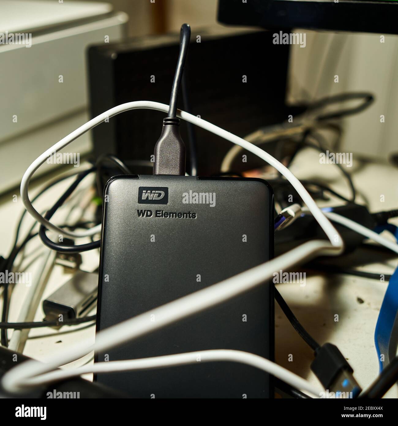 Il disco rigido esterno Western Digital con il logo WD per il collegamento al computer si trova in un groviglio di cavi su una scrivania a Gifhorn, Germania, gennaio 16. Foto Stock