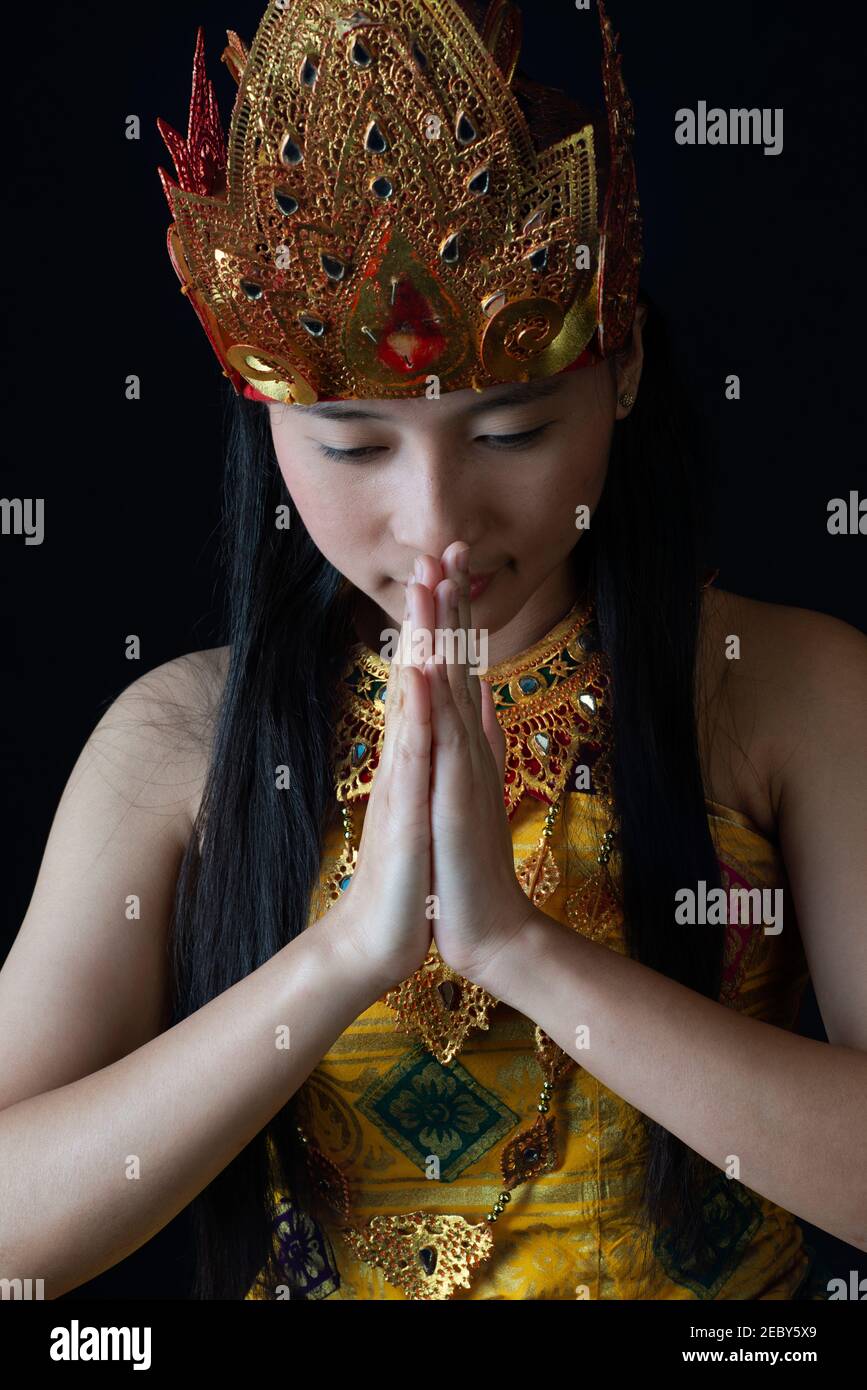 Ragazza indonesiana vestita con le mani in abito tradizionale giavanese In un gesto di saluto Foto Stock