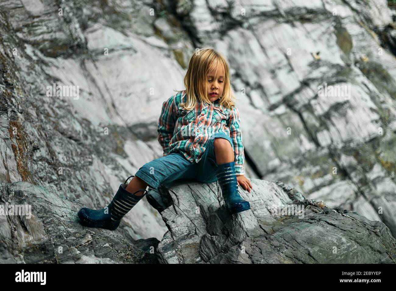 Un piccolo preschooler sta arrampicando su alcune rocce nel autunno Foto Stock