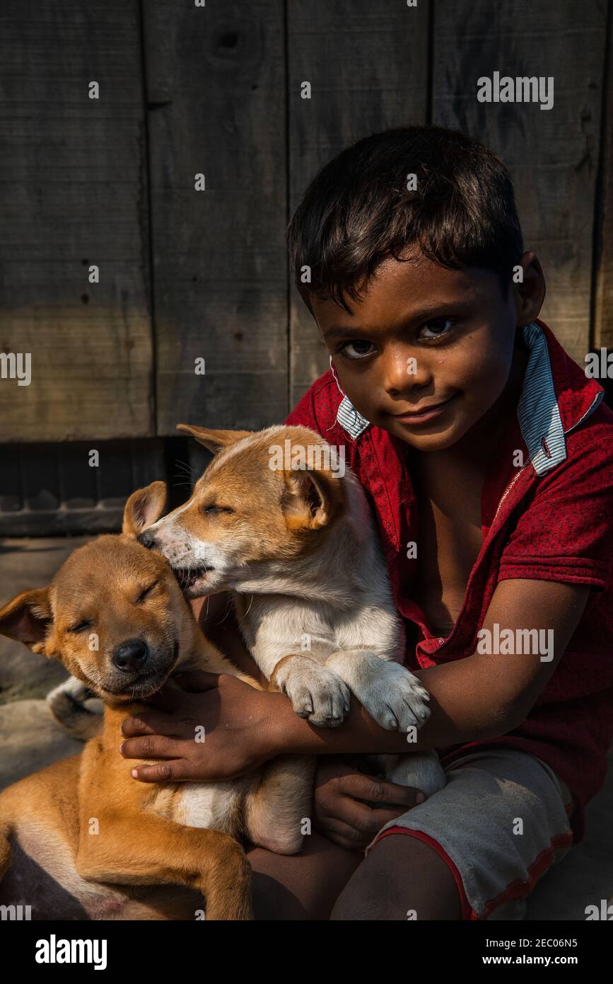 Un ragazzo sta giocando con un cane sulla strada site.Khulna, Bangladesh.February 7,2020. Foto Stock
