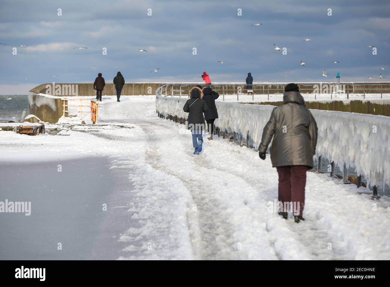 Gefrorenes Meerwasser ist an der Mole vom Leuchtturm Travemünde in Lübeck-Travemünde zu sehen. Foto Stock