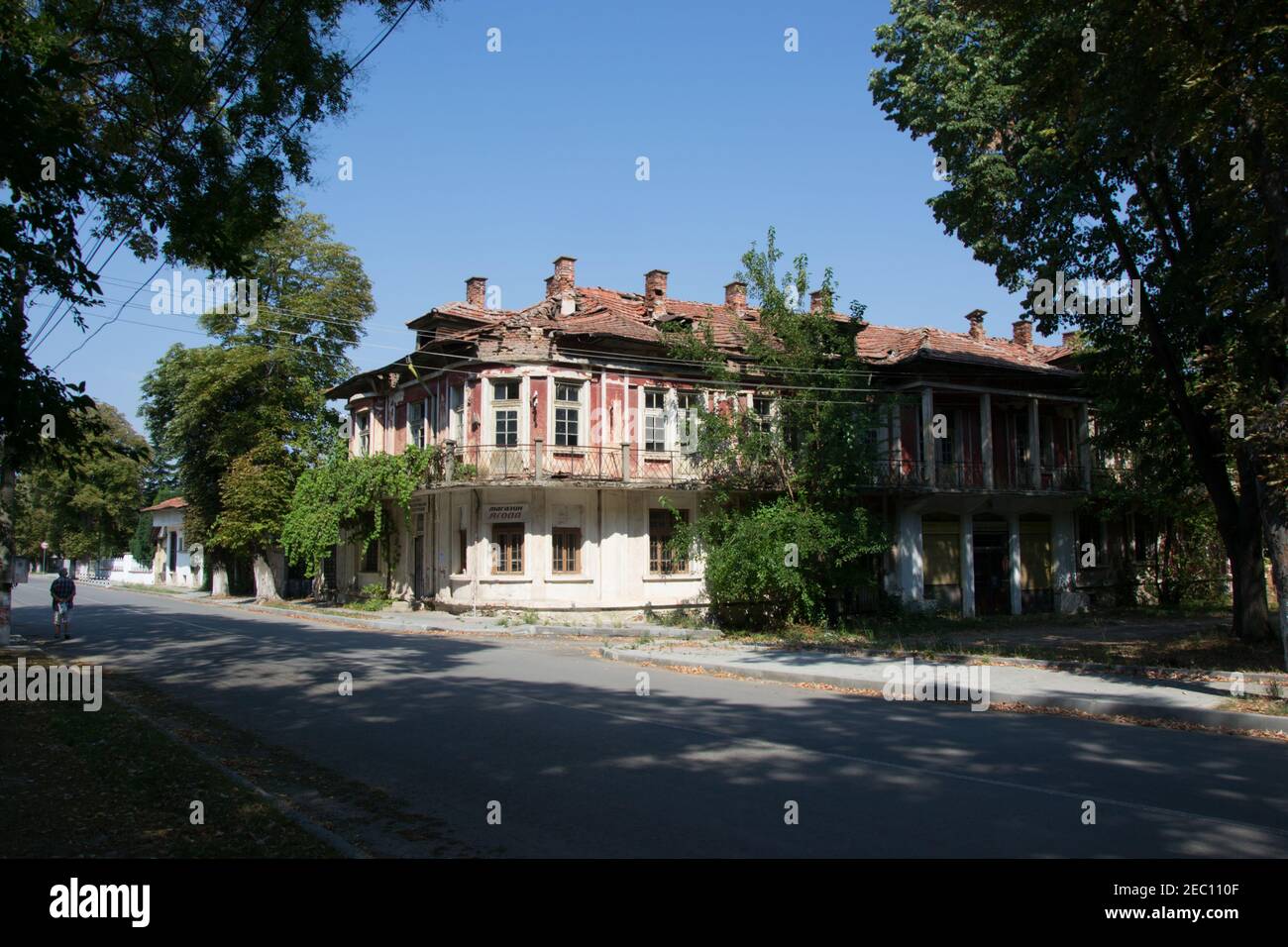 8 agosto 2020, selo Qgoda, Bulgaria - casa abbandonata villaggio coperto di piante verdi, finestra rotta, danni su una vecchia casa sulla strada Foto Stock