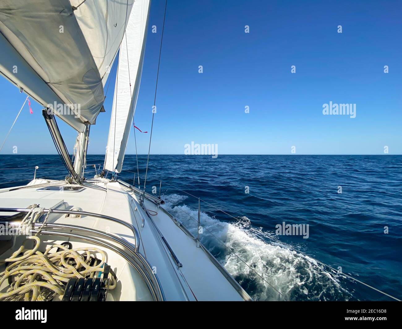 Yacht a vela lontano dalle teste del porto di Sydney, in una giornata tranquilla e soleggiata. Vista dall'abitacolo della barca sull'orizzonte, con l'oceano blu calmo Foto Stock