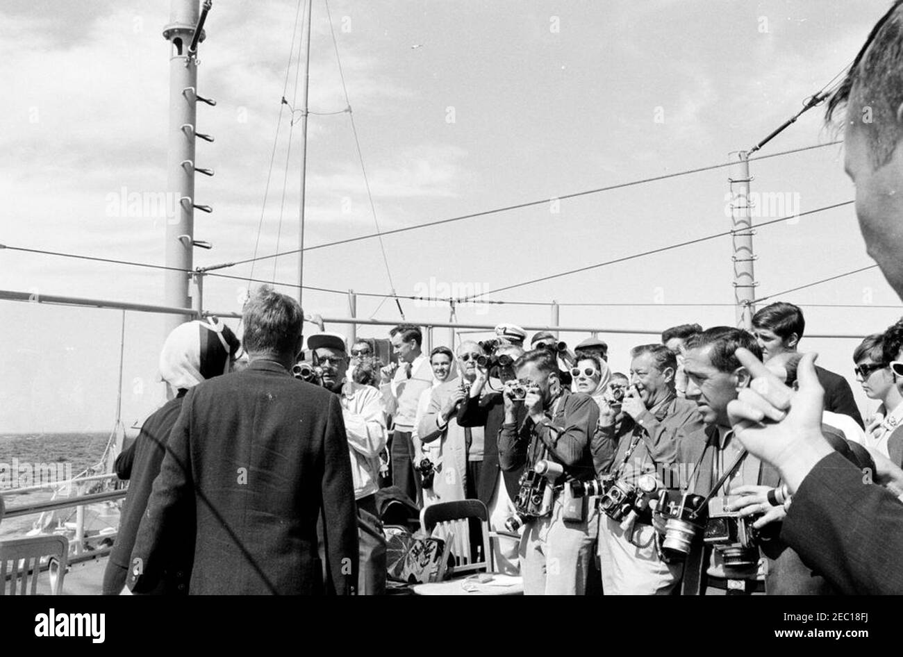 Il presidente Kennedy si accuda alla prima gara di Coppa Americau0027s. Il presidente John F. Kennedy e la First Lady Jacqueline Kennedy (entrambi a sinistra) partecipano alla prima gara della Coppa Americau0027s 1962 a bordo della USS Joseph P. Kennedy, Jr. Anche nella foto: Assistente Segretario del Tesoro, James A. Reed; Senatore Edmund S. Muskie (Maine); Anita Marcus Fay (moglie del Sottosegretario della Marina, Paul u0022Redu0022 Fay); Hugh D. Auchincloss; Janet Lee Auchincloss; fotografo della Casa Bianca, capo Robert L. Knudsen; John Forbes Kerry; Janet Jennings Auchincloss. I fotografi non identificati osservano. Newport, Rhode Foto Stock