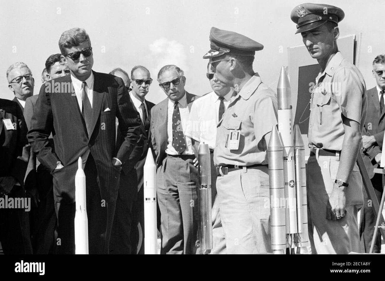 Visita delle installazioni della NASA: Cape Canaveral Florida, 14:31. Il presidente John F. Kennedy (indossando occhiali da sole) vede i modelli dei missili Titan II e Titan III, durante un tour del complesso di lancio del Titan presso la stazione dell'aeronautica di Cape Canaveral, Cape Canaveral, Florida; Direttore delle operazioni di Range Safety con la gamma di test Eastern presso la base dell'aeronautica di Patrick, il colonnello Dan F. Thompson (centro a destra), ha informato il presidente Kennedy. In piedi: Responsabile delle operazioni della Florida per il Centro Spacecraft presidiato, G. Merritt Preston; capo consulente scientifico del Ministero della Difesa della Gran Bretagna Foto Stock