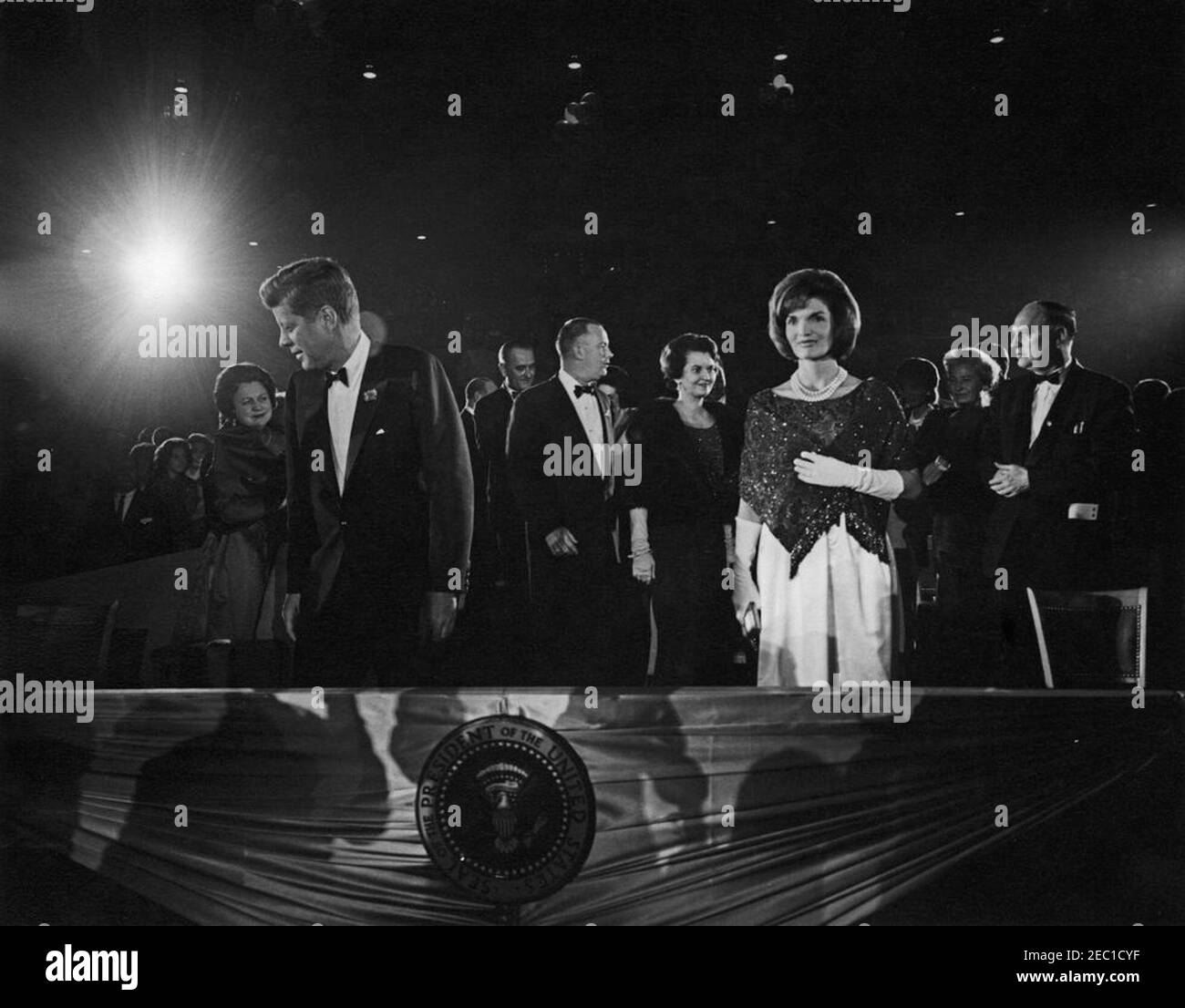 Secondo saluto inaugurale alla cena del Presidente, 19:30. Il presidente John F. Kennedy (a sinistra) e la First Lady Jacqueline Kennedy (a destra) partecipano al secondo saluto inaugurale al presidente, commemorando il secondo anniversario dell'inaugurazione del presidente Kennedyu0027s. Bedford S. Wynne, presidente dell'evento (in profilo), è a destra del presidente; il vicepresidente Lyndon B. Johnson e Lady Bird Johnson (per lo più nascosto) sono dietro il sig. Wynne. A destra della First Lady sono il presidente del Comitato Nazionale Democratico (DNC) John M. Bailey; Maureen Hayes Mansfield, moglie del senatore Mike Mansfie Foto Stock