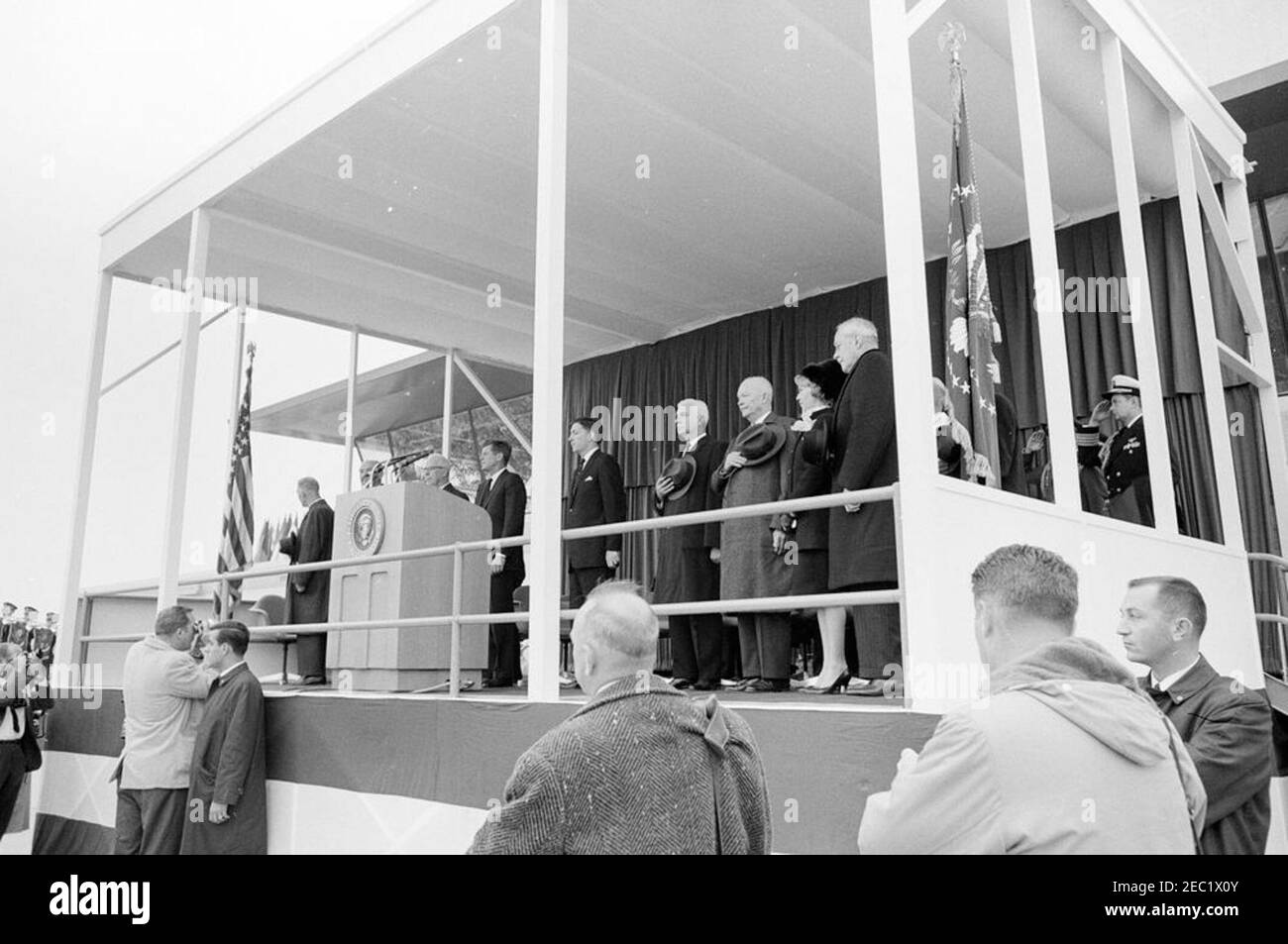 Cerimonie di dedica, aeroporto internazionale di Dulles, 11:12. Il presidente John F. Kennedy, l'ex presidente, il generale Dwight D. Eisenhower, ed altri stanno per l'inno nazionale durante la cerimonia di dedizione per l'aeroporto internazionale di Dulles, che prende il nome dal defunto Segretario di Stato, John Foster Dulles. Sulla piattaforma speakersu2019 (L-R): Cappellano del Senato degli Stati Uniti, il reverendo Frederick Brown Harris; Segretario di Stato, Dean Rusk; Giustizia Capo della Corte Suprema, Earl Warren; Presidente Kennedy; Amministratore della Federal Aviation Agency (FAA), Najeeb Halaby; Governatore della Virginia, Alberti Foto Stock