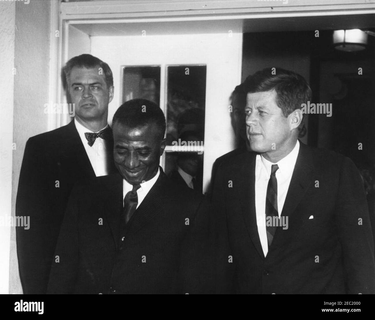 Incontro con Sylvanus Olympio, presidente del Togo, 14:53. Il presidente John F. Kennedy e il presidente del Togo, Sylvanus Olympio (centro), escono dalla Casa Bianca dopo il loro incontro e pranzo. Il Segretario di Stato aggiunto per gli Affari africani, G. Mennen u201cSoapyu201d Williams, si trova dietro il Presidente Olympio. Ingresso dell'ala ovest, Casa Bianca, Washington, D.C. Foto Stock