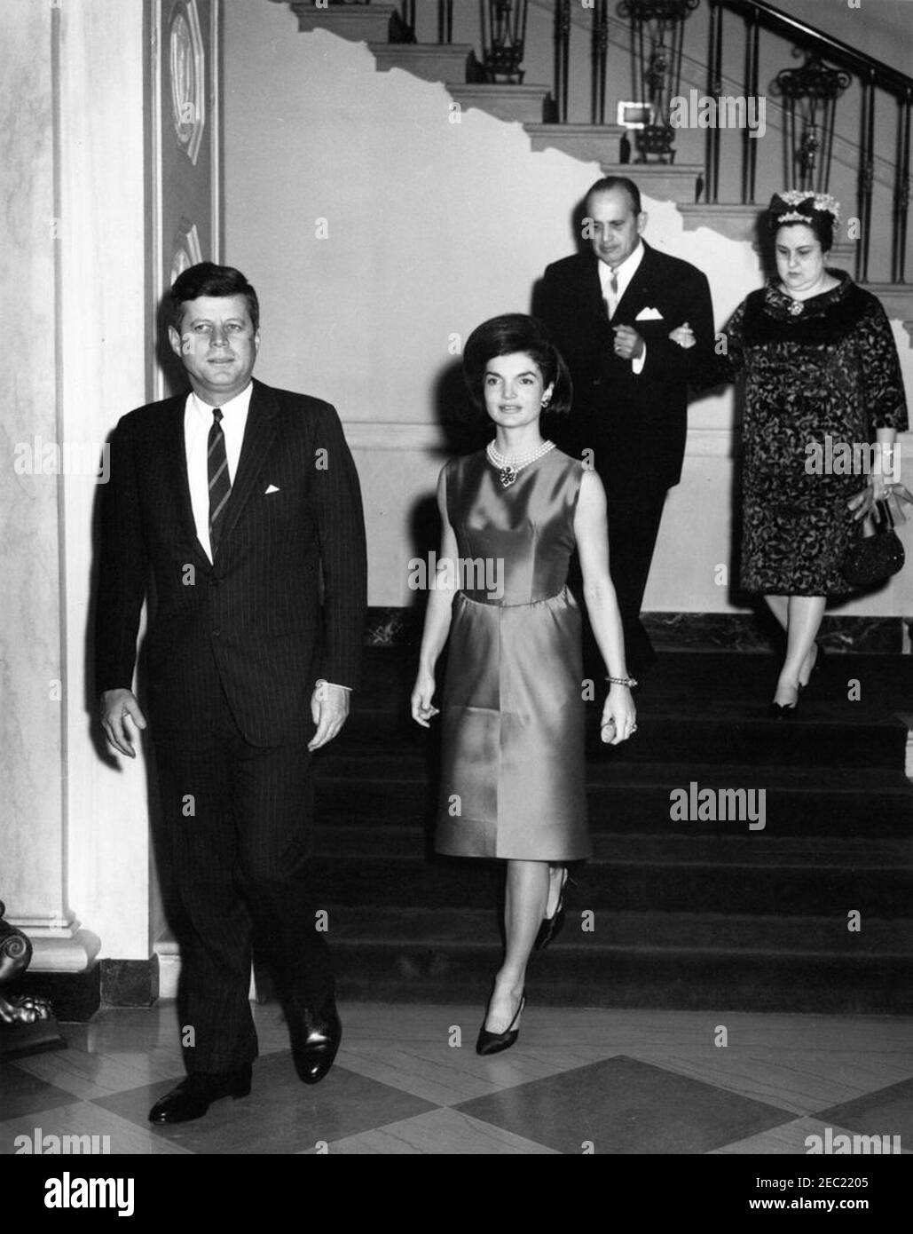 Accoglienza diplomatica alle 18:30. Il presidente John F. Kennedy e la First Lady Jacqueline Kennedy arrivano nella sala d'ingresso per un ricevimento diplomatico alla Casa Bianca. L'Ambasciatore del Nicaragua e Decano del corpo Diplomatico, il Dr. Guillermo Sevilla-Sacasa, e Lillian Somoza de Sevilla-Sacasa discendono la Grande Scala. White House, Washington, D.C. Foto Stock