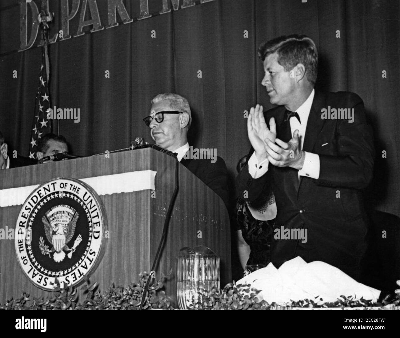 Discorso alla cerimonia del 50° anniversario del Dipartimento del lavoro, ore 10:26. Il presidente John F. Kennedy applaude la Corte Suprema di giustizia e l'ex Segretario del lavoro, Arthur Goldberg (al leggio), durante una cena che celebra il 50° anniversario del Dipartimento del lavoro. Sheraton Park Hotel, Washington, D.C. Foto Stock