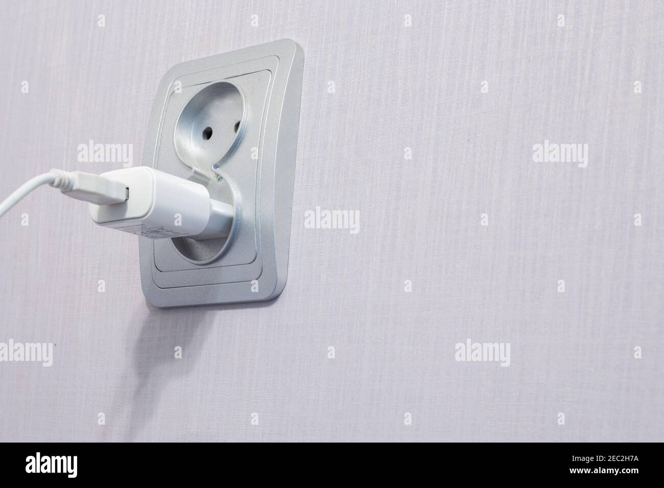 il cavo è collegato a una presa per caricare il telefono, un luogo per il testo Foto Stock