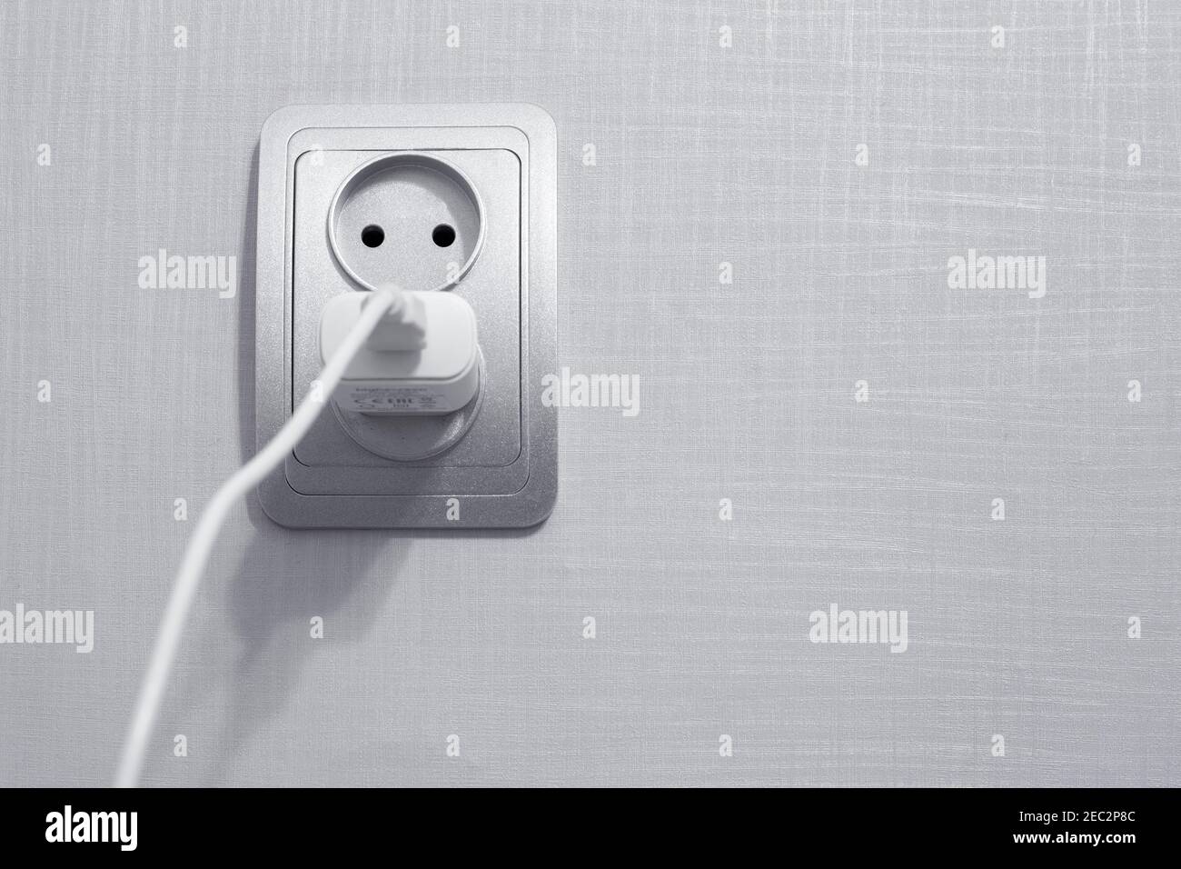 il cavo è collegato a una presa per caricare il telefono, un luogo per il testo Foto Stock