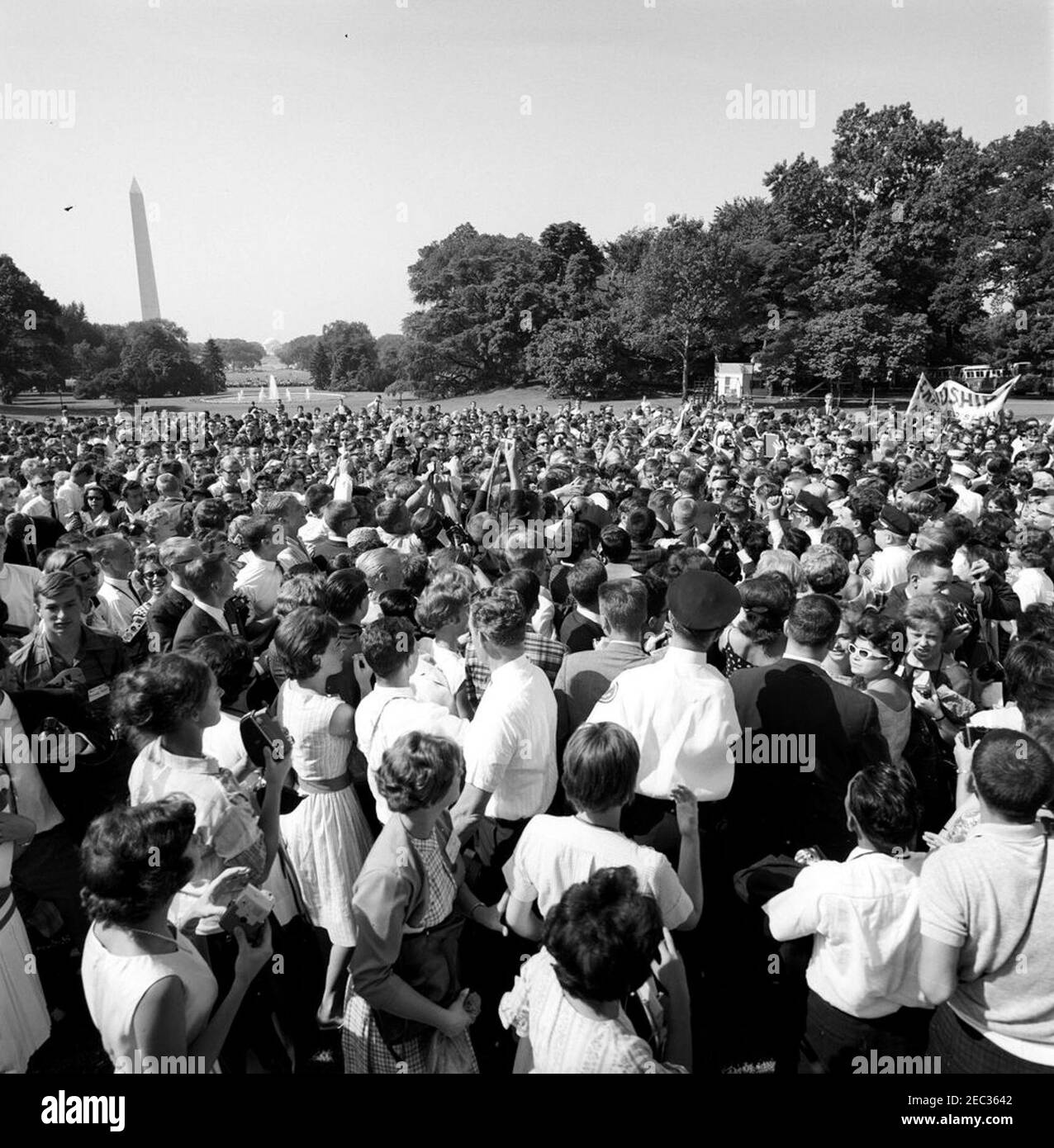 Visita degli studenti dell'American Field Service alle 9:50. Il presidente John F. Kennedy (centro a destra, in folla) visita con gli studenti del servizio sul campo americano (AFS) sul prato sud della Casa Bianca, Washington, D.C. il monumento di Washington e il Jefferson Memorial sono visibili in lontananza. Foto Stock