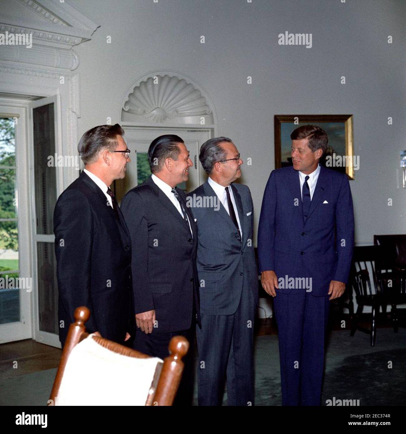 Incontro con il governatore Grant Sawyer del Nevada e i senatori Alan Bible e Howard W. Cannon (Nevada), 16:35. Il presidente John F. Kennedy si trova in piedi con funzionari del Nevada. Da sinistra a destra: Il governatore Grant Sawyer, il senatore Howard W. Cannon, la Bibbia del senatore Alan e il presidente Kennedy. Ufficio ovale, Casa Bianca, Washington, D.C. Foto Stock