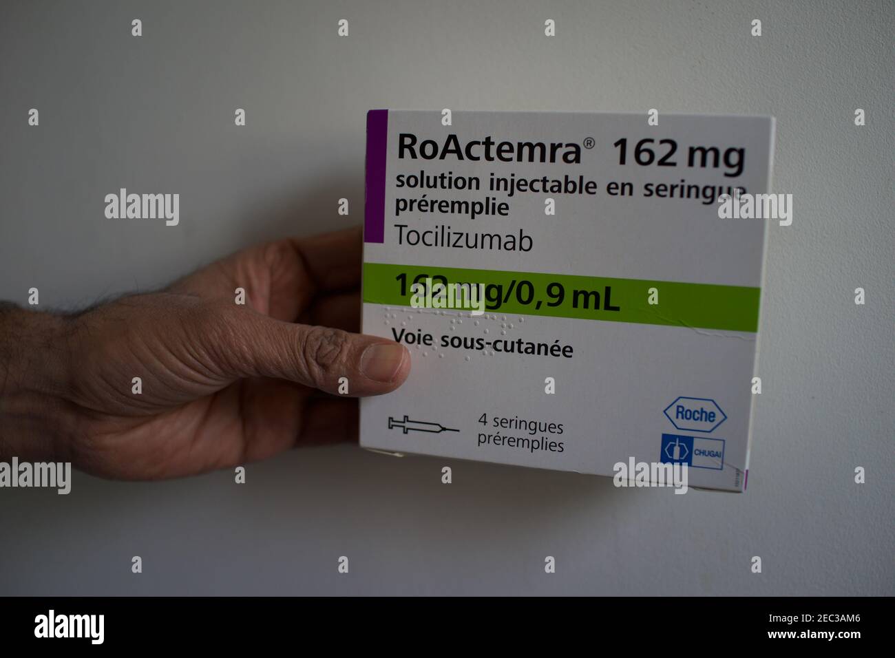 Mano che tiene Tocilizumab, RoActemra farmaco scatola, artrite farmaco utilizzato nel trattamento di Covid-19 Foto Stock