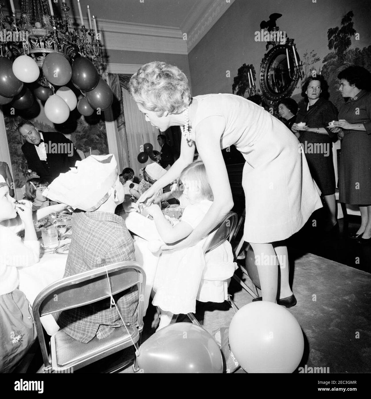 Festa di compleanno per Caroline Kennedy e John F. Kennedy, Jr. Caroline Kennedy gioca con un telefono giocattolo durante una festa di compleanno congiunta per lei e suo fratello, John F. Kennedy, Jr.; una donna non identificata (che tiene il telefono) si trova dietro Caroline. Anche nella foto: Maria Shriver; Janet Auchincloss; maggiordomo della Casa Bianca, John W. Ficklin; fotografo della Casa Bianca, capo Robert L. Knudsen. Presidentu2019s Dining Room (Residence), Casa Bianca, Washington, D.C. Foto Stock