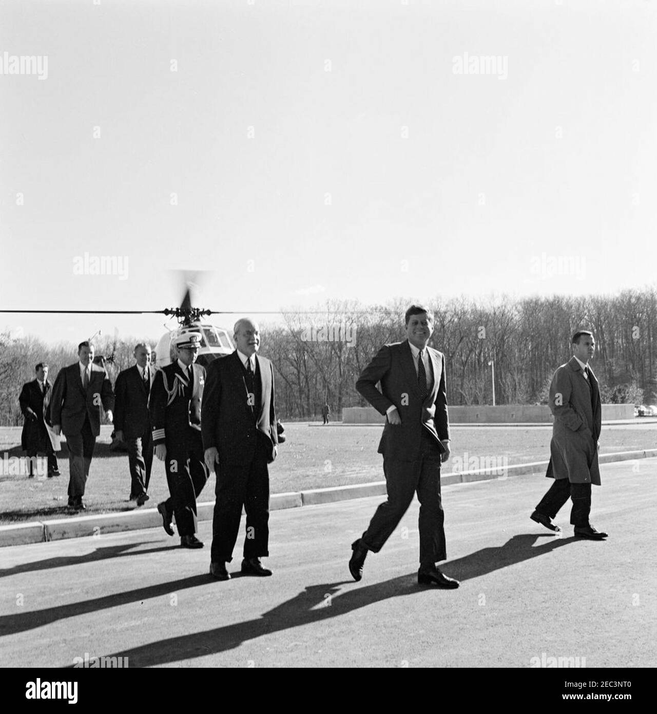 Presentazione della Medaglia di sicurezza Nazionale a Allen Dulles, 11:00. Il presidente John F. Kennedy arriva alla sede centrale della Central Intelligence Agency (CIA) a Langley, Virginia, per presentare la Medaglia di sicurezza Nazionale a Allen W. Dulles, direttore in pensione della CIA. Dietro il presidente Kennedy camminano il sig. Dulles, l'Aide navale al capitano del presidente Tazewell Shepard, il generale dell'esercito degli Stati Uniti Maxwell D. Taylor e il segretario della difesa Robert S. McNamara. L'Agente di Servizio Segreto della Casa Bianca Bill Duncan cammina a destra del presidente Kennedy. Gli elicotteri dell'esercito degli Stati Uniti sono visibili nella b Foto Stock