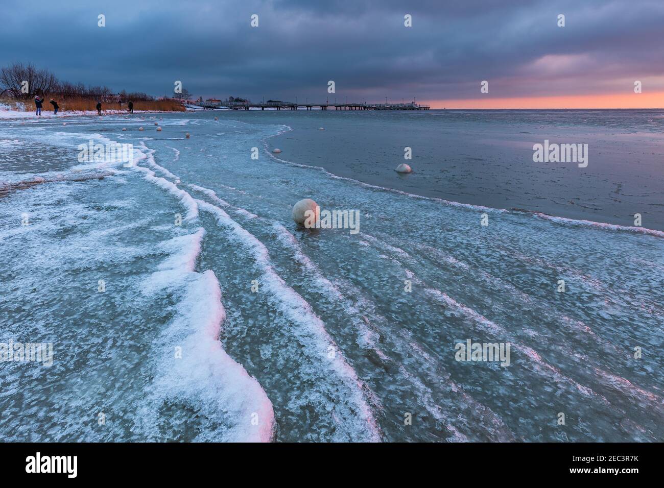 Paesaggio invernale in Jastarnia. Palle di neve naturale sulla spiaggia del Golfo di Danzica. Pier sullo sfondo. Bellissimo tramonto. Polonia. Foto Stock