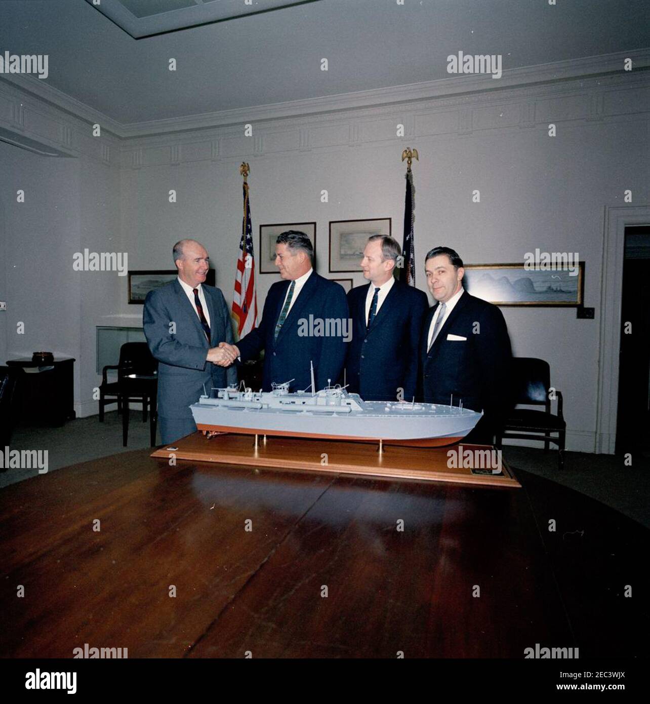 Presentazione di un modello di barca PT per il presidente Kennedy. Assistente speciale al Presidente Dave Powers visite con tre rappresentanti non identificati del Washington International Boat and Sport Show nella Fish Room della Casa Bianca, Washington, D.C. seduto sul tavolo è un modello di PT Boat 109 che hanno presentato al Presidente John F. Kennedy. [Vedi anche MO 63.1212, u201cModello di PT 109.u201d] Foto Stock